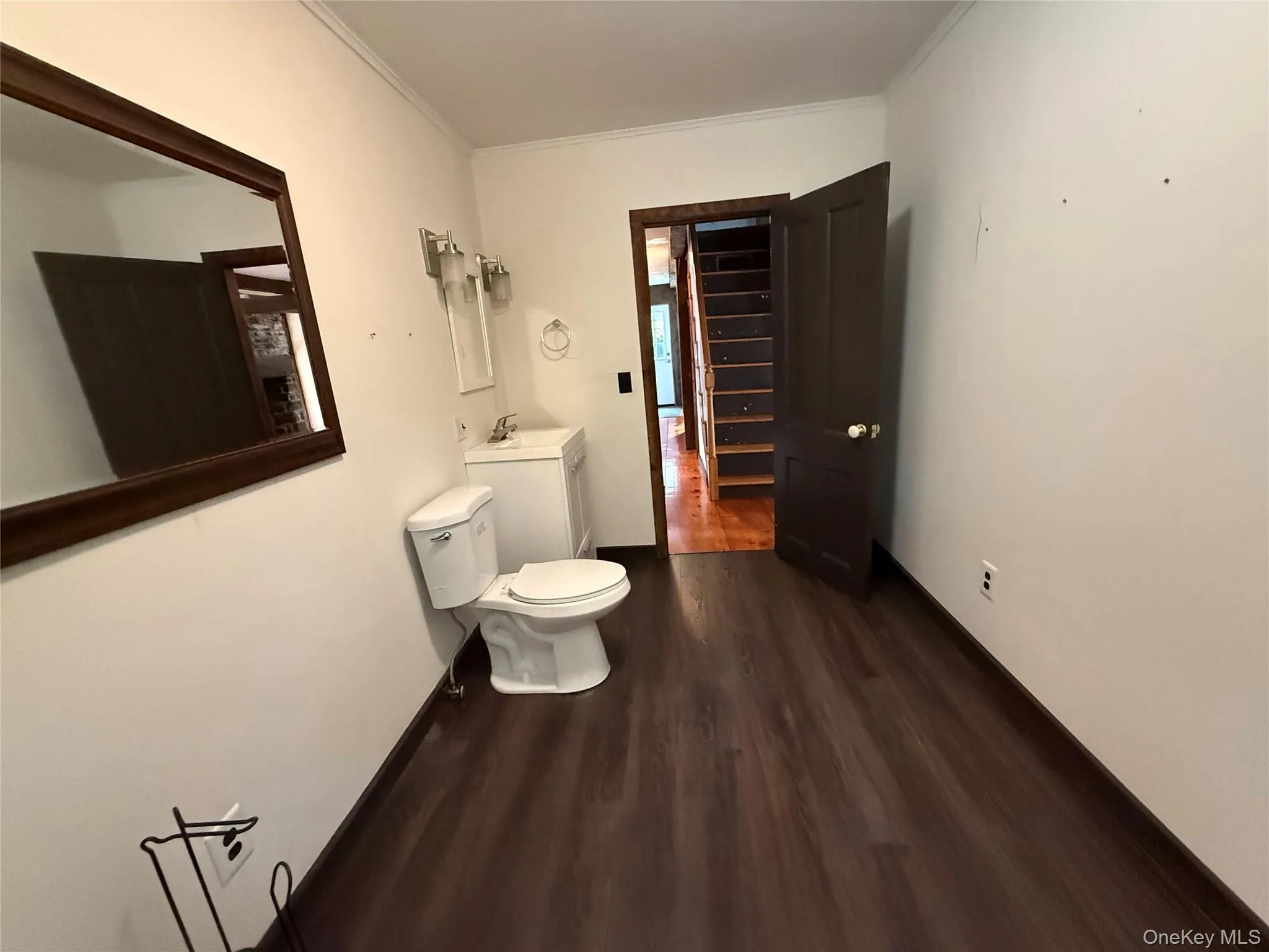 Half bath with dark wood-style flooring, ornamental molding, and vanity Half bath with dark wood-style flooring, ornamental molding, and vanity