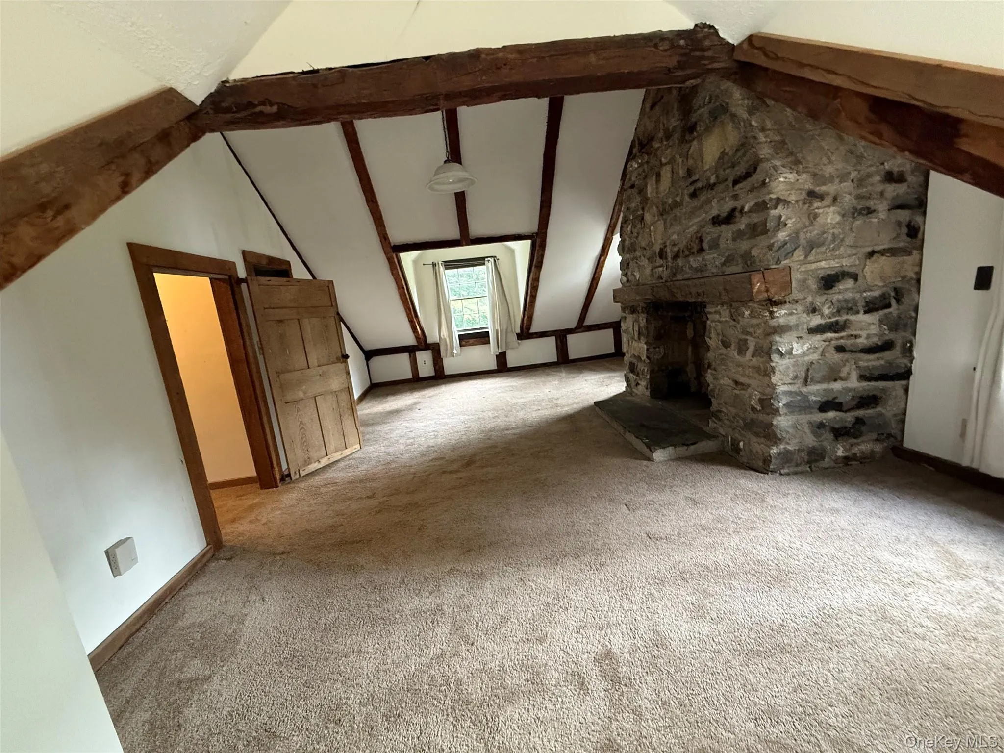 Unfurnished living room with carpet and a stone fireplace Unfurnished living room with carpet and a stone fireplace