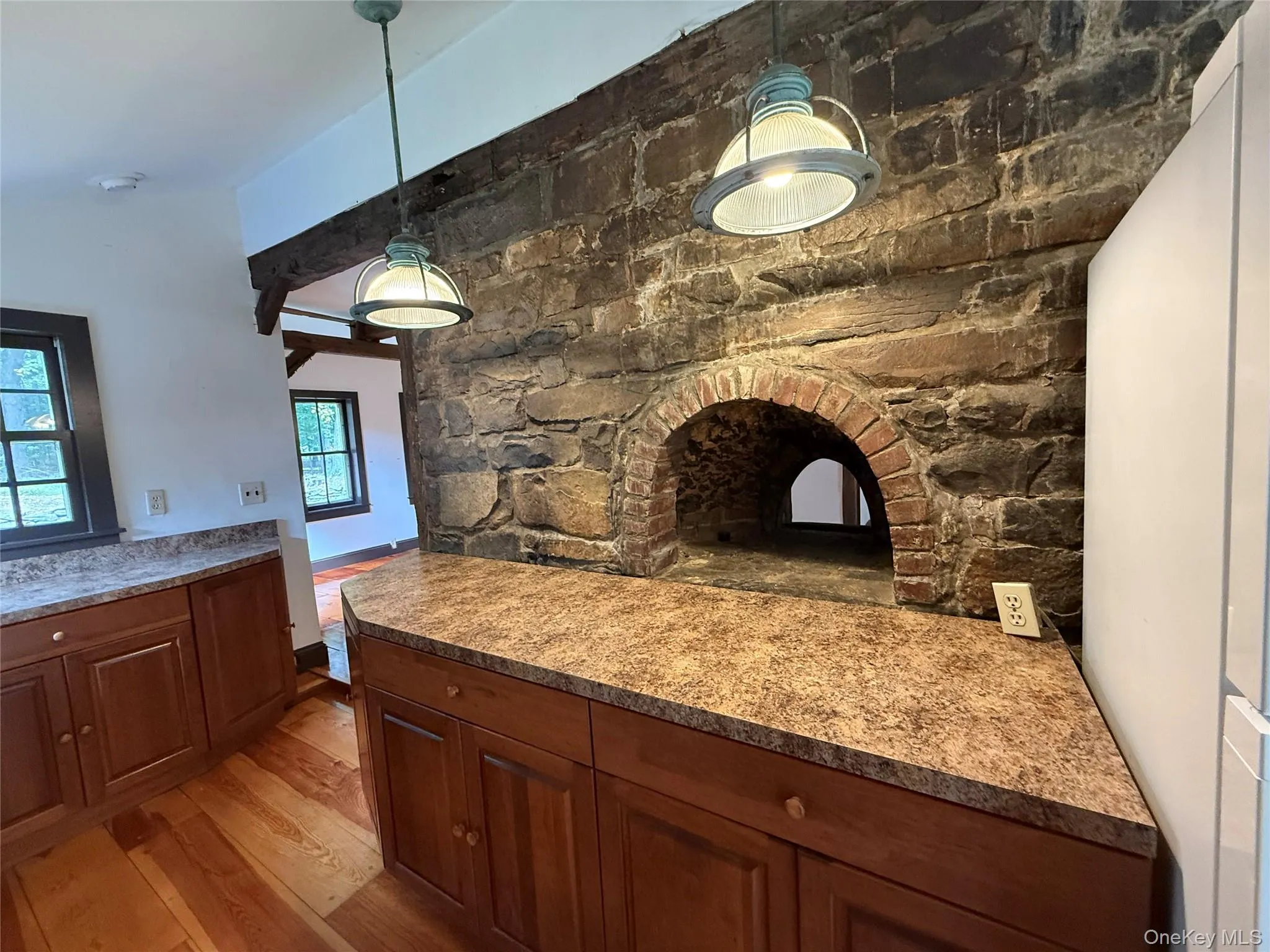Kitchen featuring light wood-type flooring, decorative light fixtures, and brown cabinetry Kitchen featuring light wood-type flooring, decorative light fixtures, and brown cabinetry