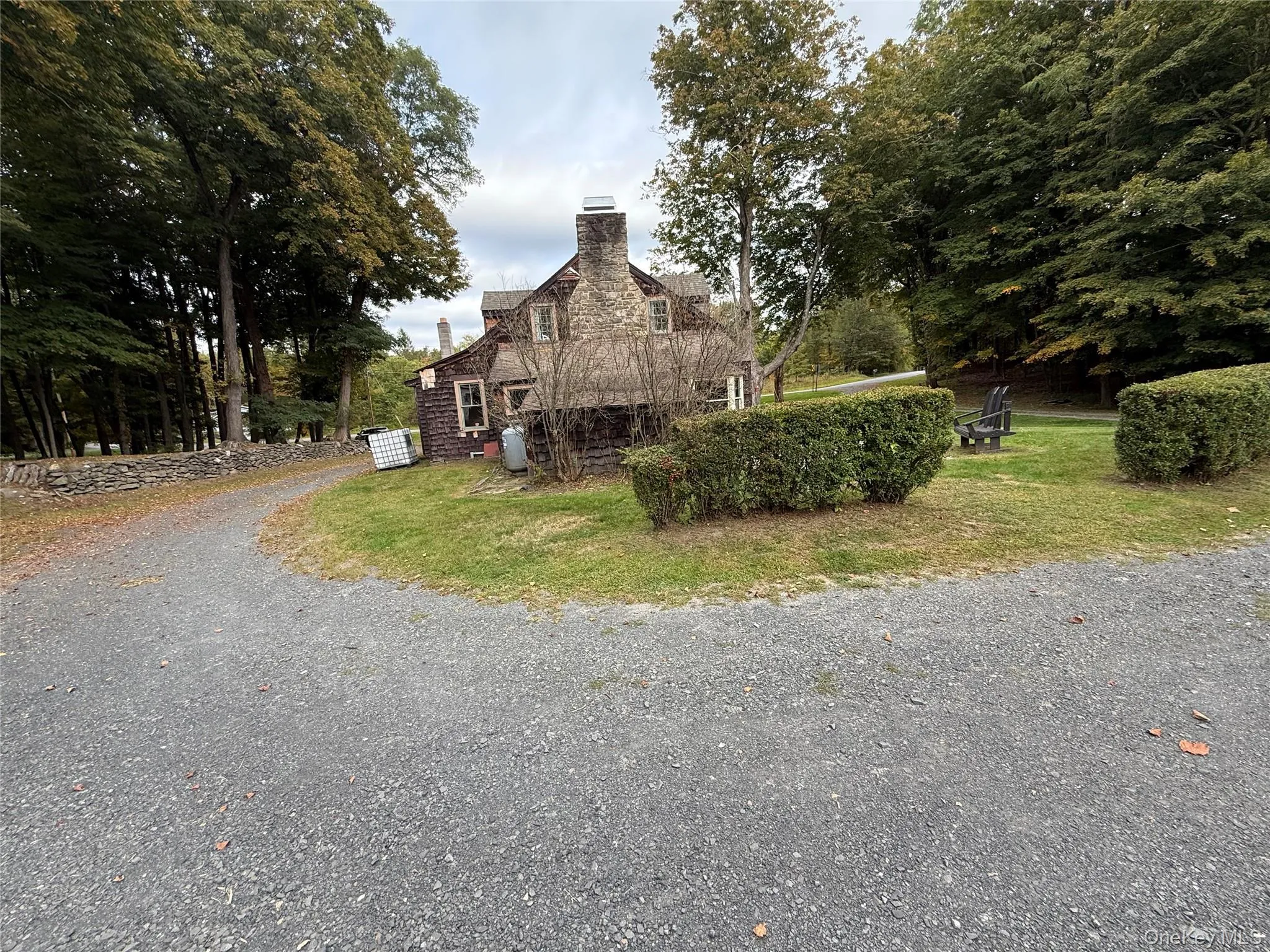View of home's exterior featuring a chimney, gravel driveway, and a lawn View of home's exterior featuring a chimney, gravel driveway, and a lawn