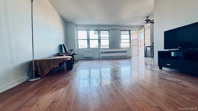 Living room featuring radiator, hardwood / wood-style floors, and a ceiling fan Living room featuring radiator, hardwood / wood-style floors, and a ceiling fan