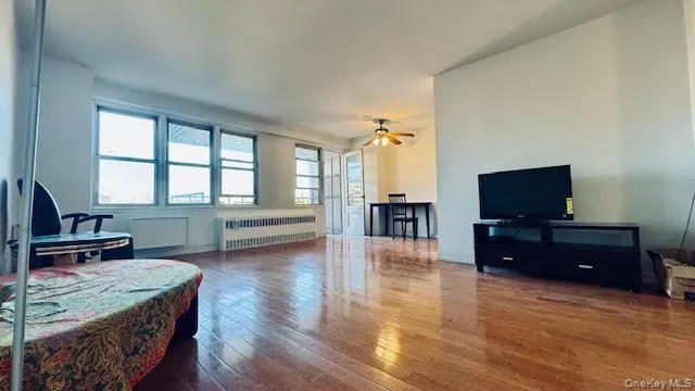 Living area with radiator, hardwood / wood-style flooring, and ceiling fan Living area with radiator, hardwood / wood-style flooring, and ceiling fan