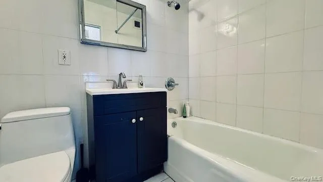 Full bath featuring tub / shower combination, tile walls, and vanity Full bath featuring tub / shower combination, tile walls, and vanity