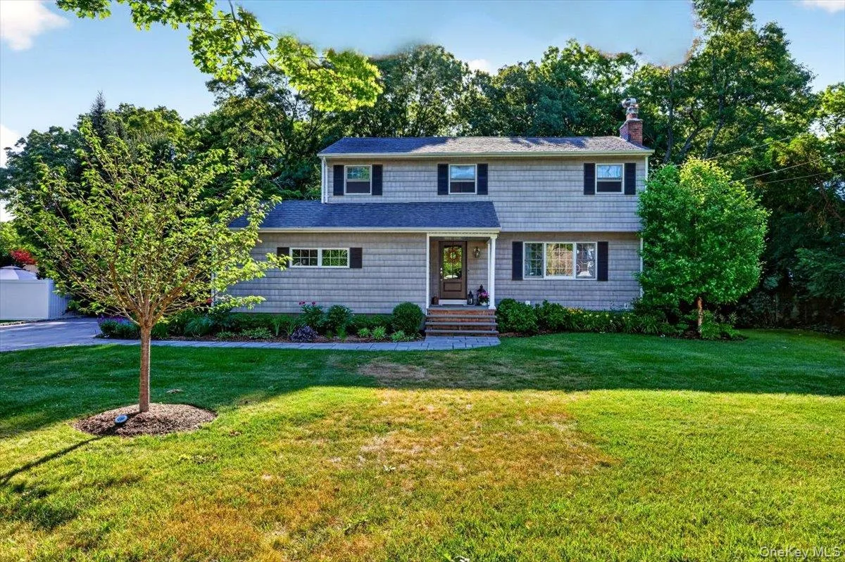 Two-story residence featuring light gray shingle siding, a dark gray shingle roof, and black window shutters Two-story residence featuring light gray shingle siding, a dark gray shingle roof, and black window shutters