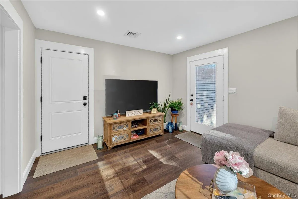 Living area featuring wood-finish flooring, recessed lighting, a paneled door, and a glass-paneled door Living area featuring wood-finish flooring, recessed lighting, a paneled door, and a glass-paneled door