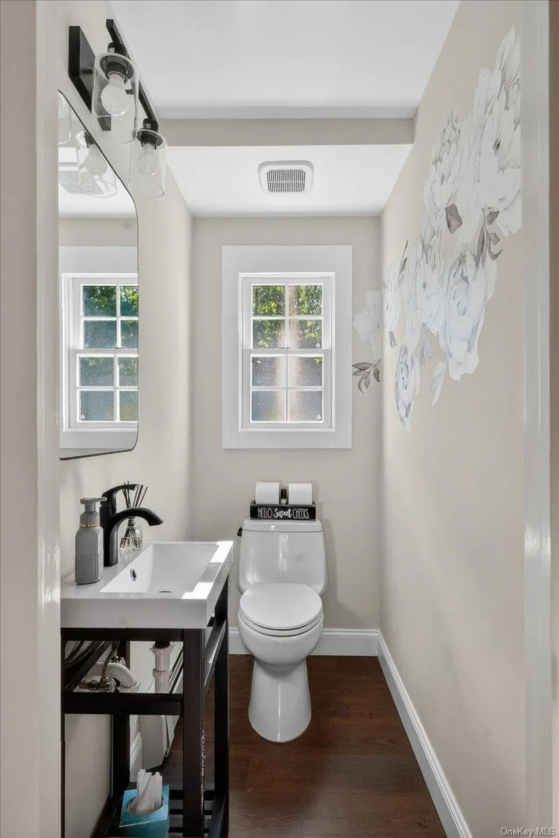 Powder room featuring a single-pane window, dark wood-finish flooring, and light-toned walls Powder room featuring a single-pane window, dark wood-finish flooring, and light-toned walls