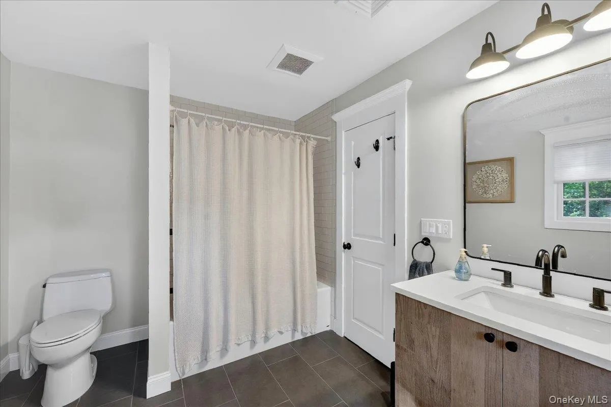 Bathroom featuring a single vanity with wood-finish cabinetry, a white countertop, and a rectangular undermount sink with a matte black faucet Bathroom featuring a single vanity with wood-finish cabinetry, a white countertop, and a rectangular undermount sink with a matte black faucet