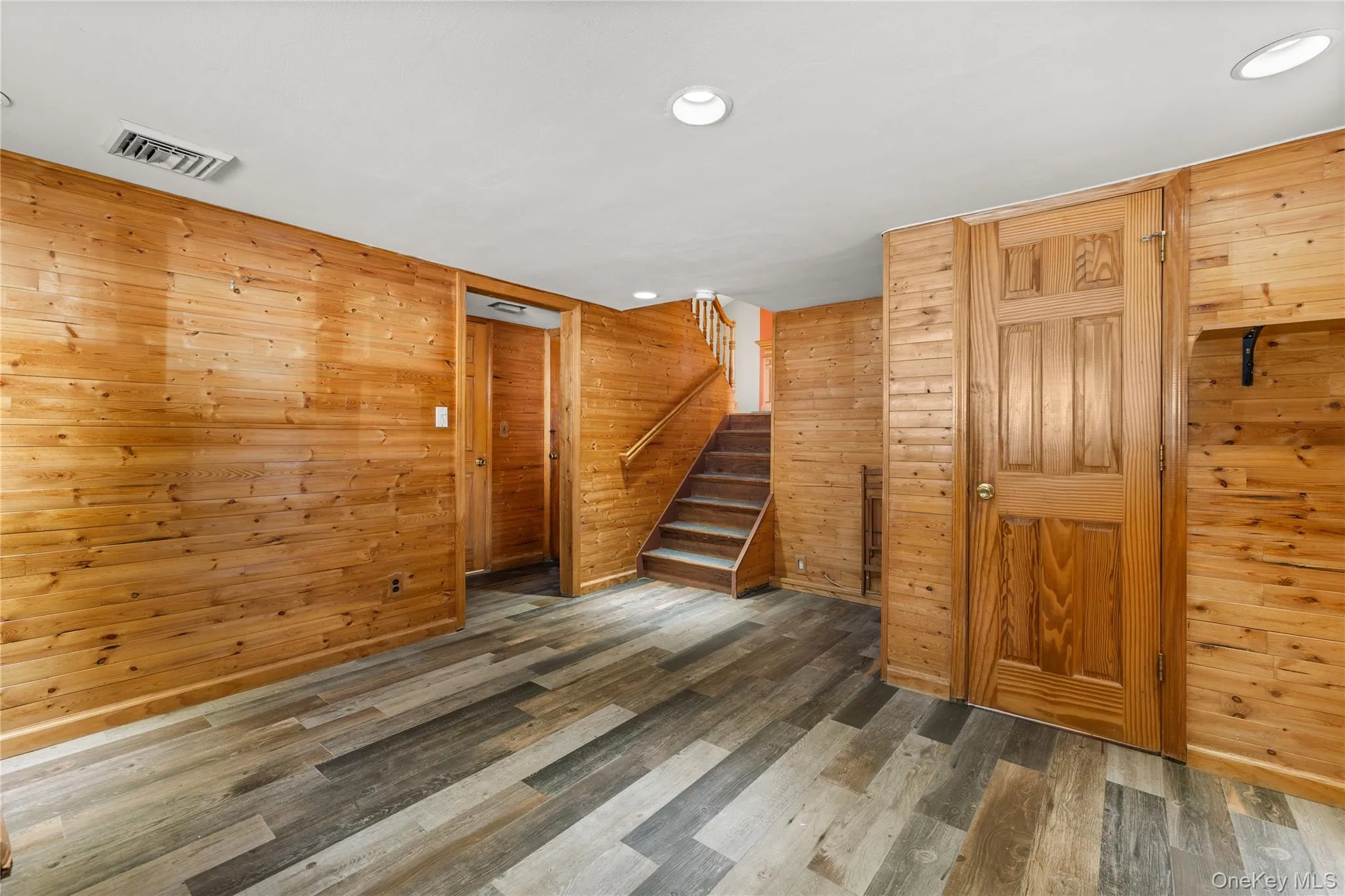 Den with wood-paneled walls, wood-finish flooring, and recessed lighting Den with wood-paneled walls, wood-finish flooring, and recessed lighting