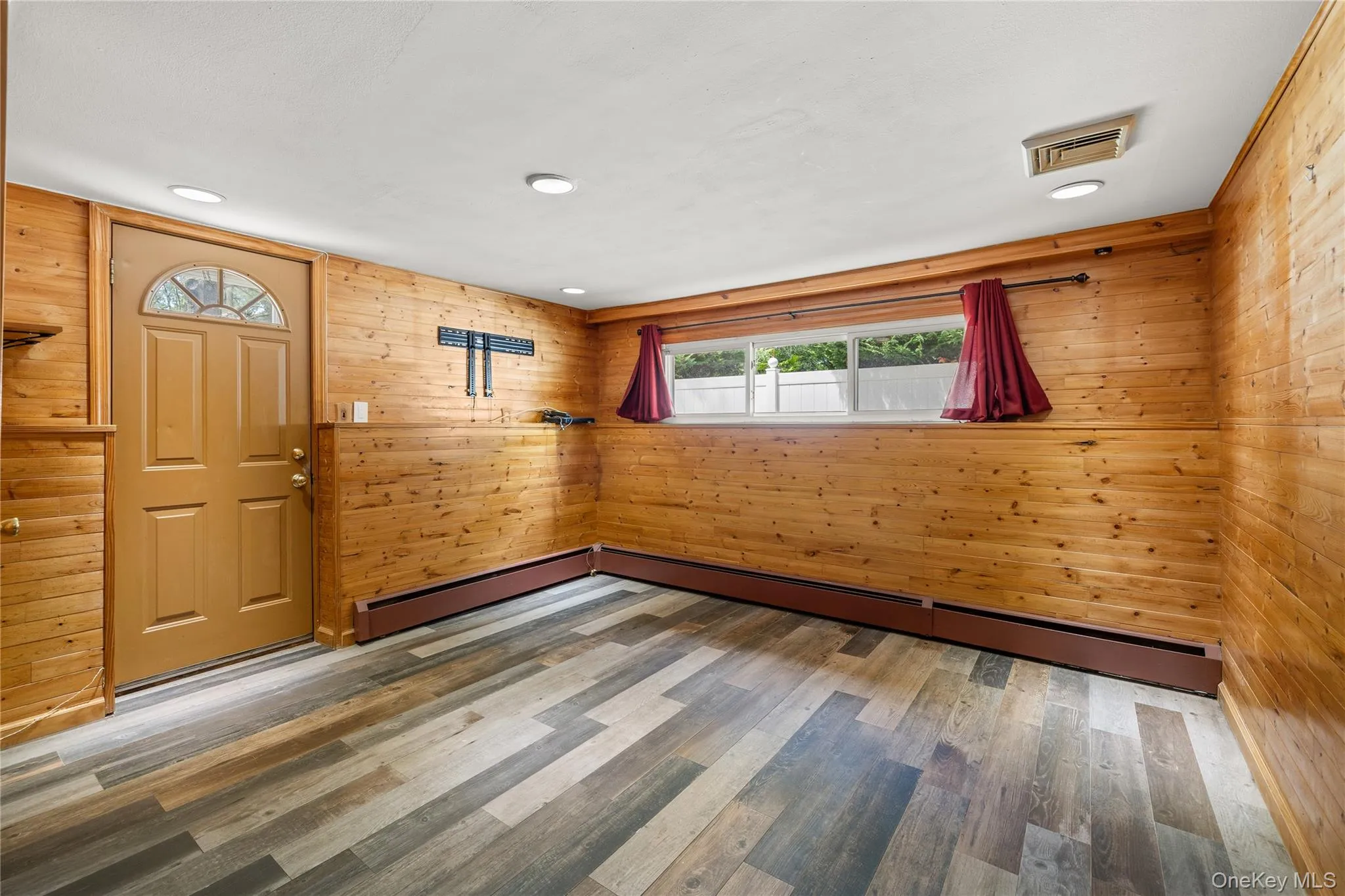 Den with wood-paneled walls, wood-finish flooring, and recessed lighting Den with wood-paneled walls, wood-finish flooring, and recessed lighting