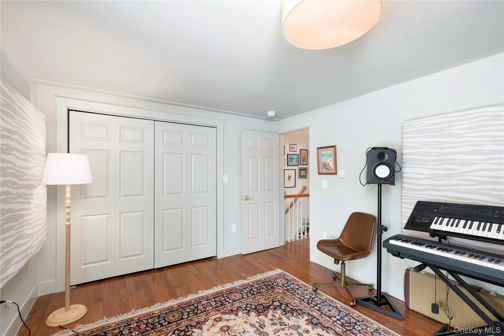 Bed room featuring wood-flooring, white paneled bifold closet doors, and white walls Bed room featuring wood-flooring, white paneled bifold closet doors, and white walls