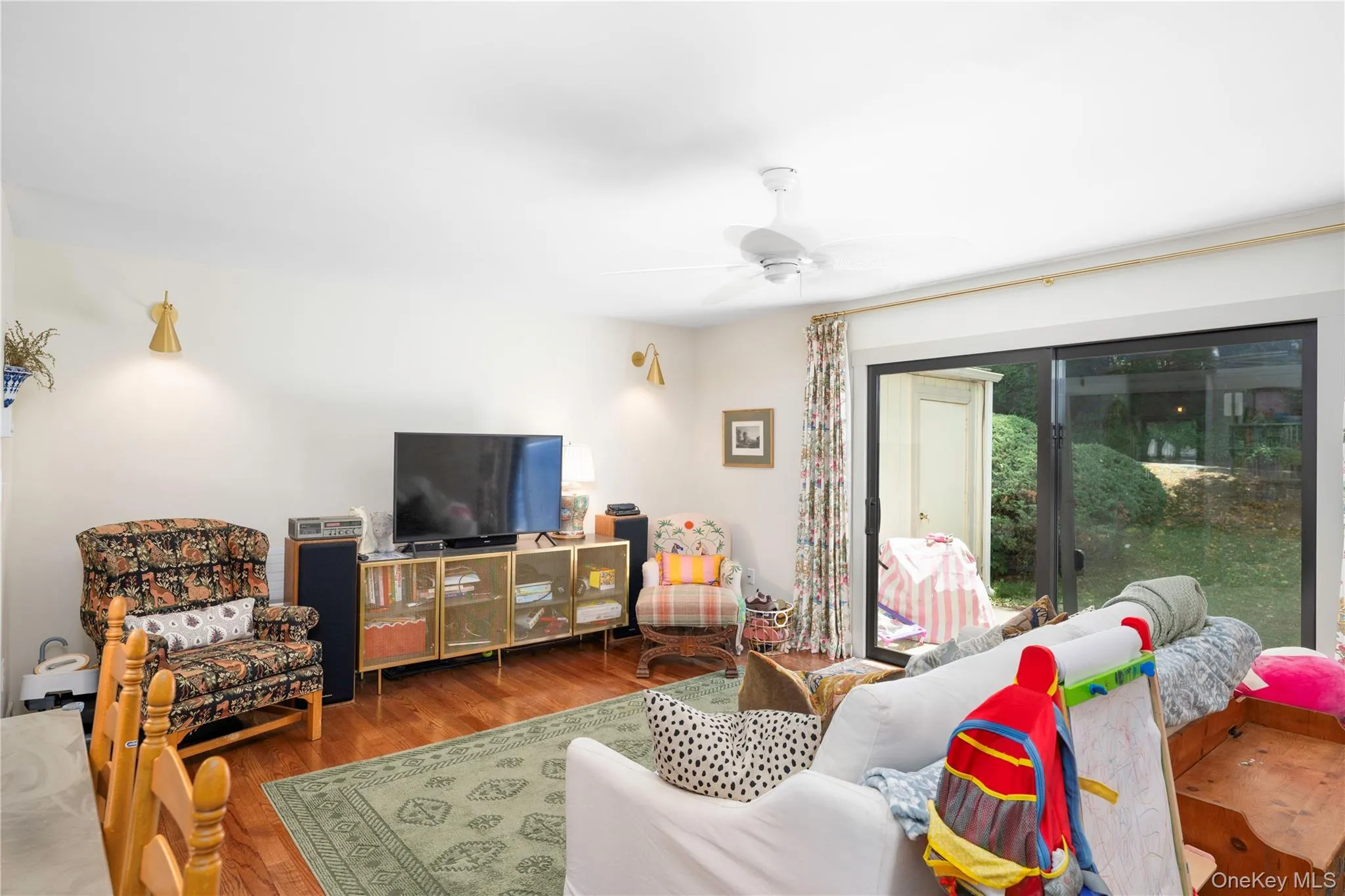 Living area featuring wood flooring, a ceiling fan, and recessed wall sconces Living area featuring wood flooring, a ceiling fan, and recessed wall sconces