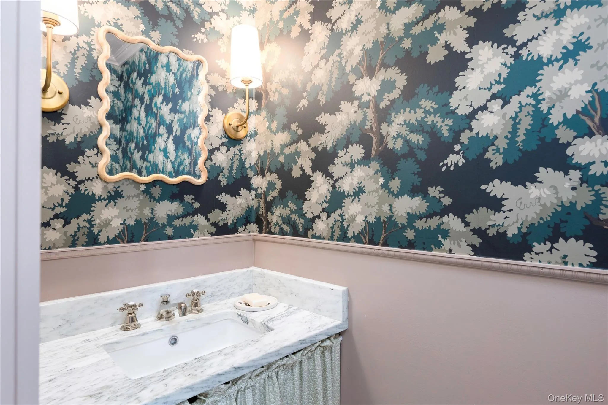 Powder room featuring a white single basin sink, a polished stone countertop, and two wall-mounted sconces with ivory shades Powder room featuring a white single basin sink, a polished stone countertop, and two wall-mounted sconces with ivory shades