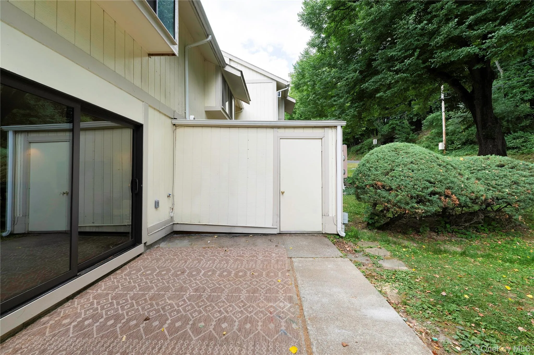 Paved patio area featuring patterned hardscaping, sliding glass door entry, and an exterior storage unit Paved patio area featuring patterned hardscaping, sliding glass door entry, and an exterior storage unit