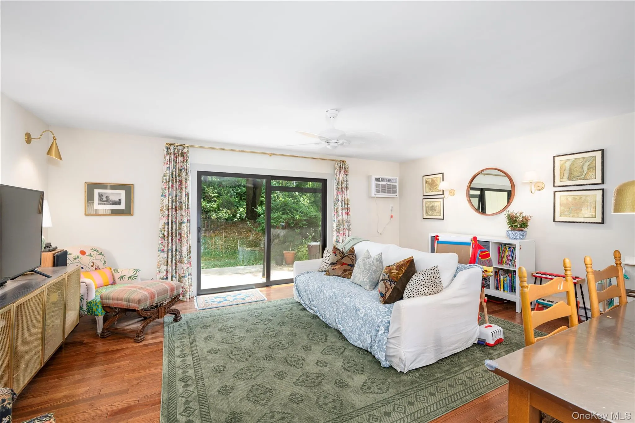 Living area featuring wood flooring, a ceiling fan, and sliding glass doors providing access to the exterior Living area featuring wood flooring, a ceiling fan, and sliding glass doors providing access to the exterior