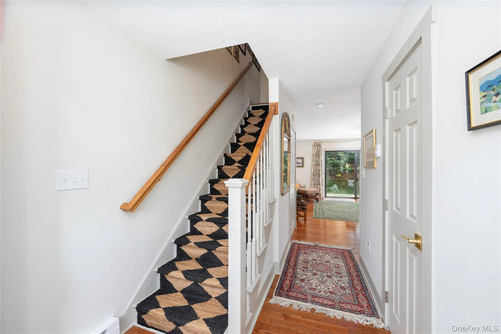 Staircase featuring a checkered runner, wood handrail, and white balusters Staircase featuring a checkered runner, wood handrail, and white balusters
