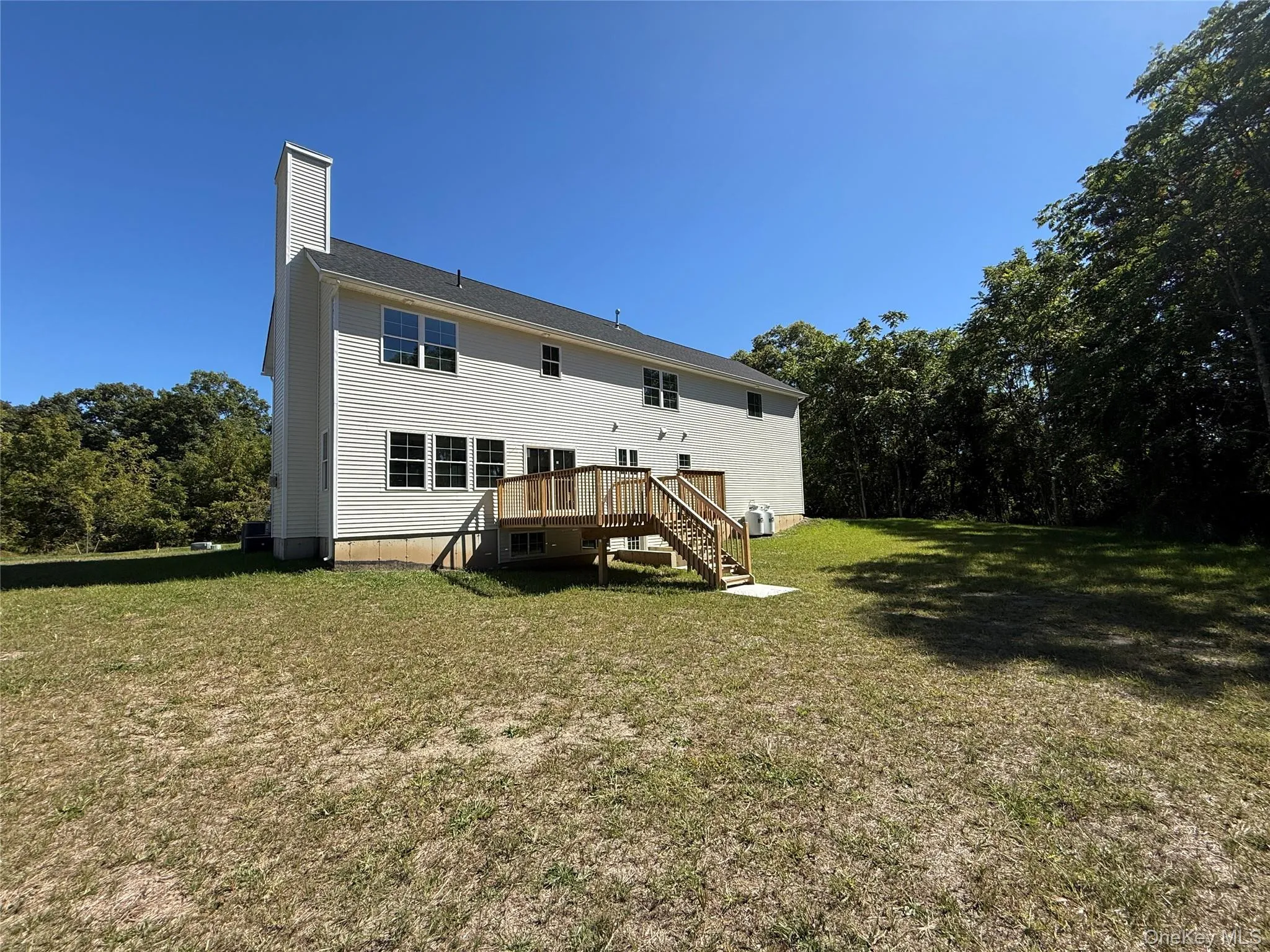 Rear view of house featuring stairway, a lawn, a chimney, and a deck Rear view of house featuring stairway, a lawn, a chimney, and a deck