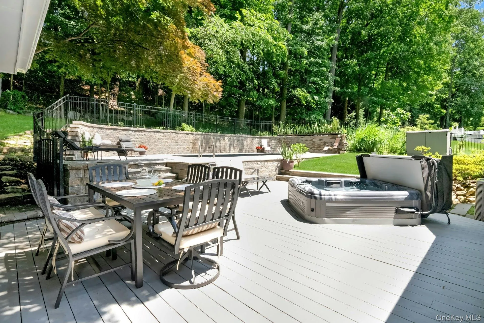 Expansive multi level deck with hot tub and saltwater pool with lighting and aluminum fencing behind. Expansive multi level deck with hot tub and saltwater pool with lighting and aluminum fencing behind.