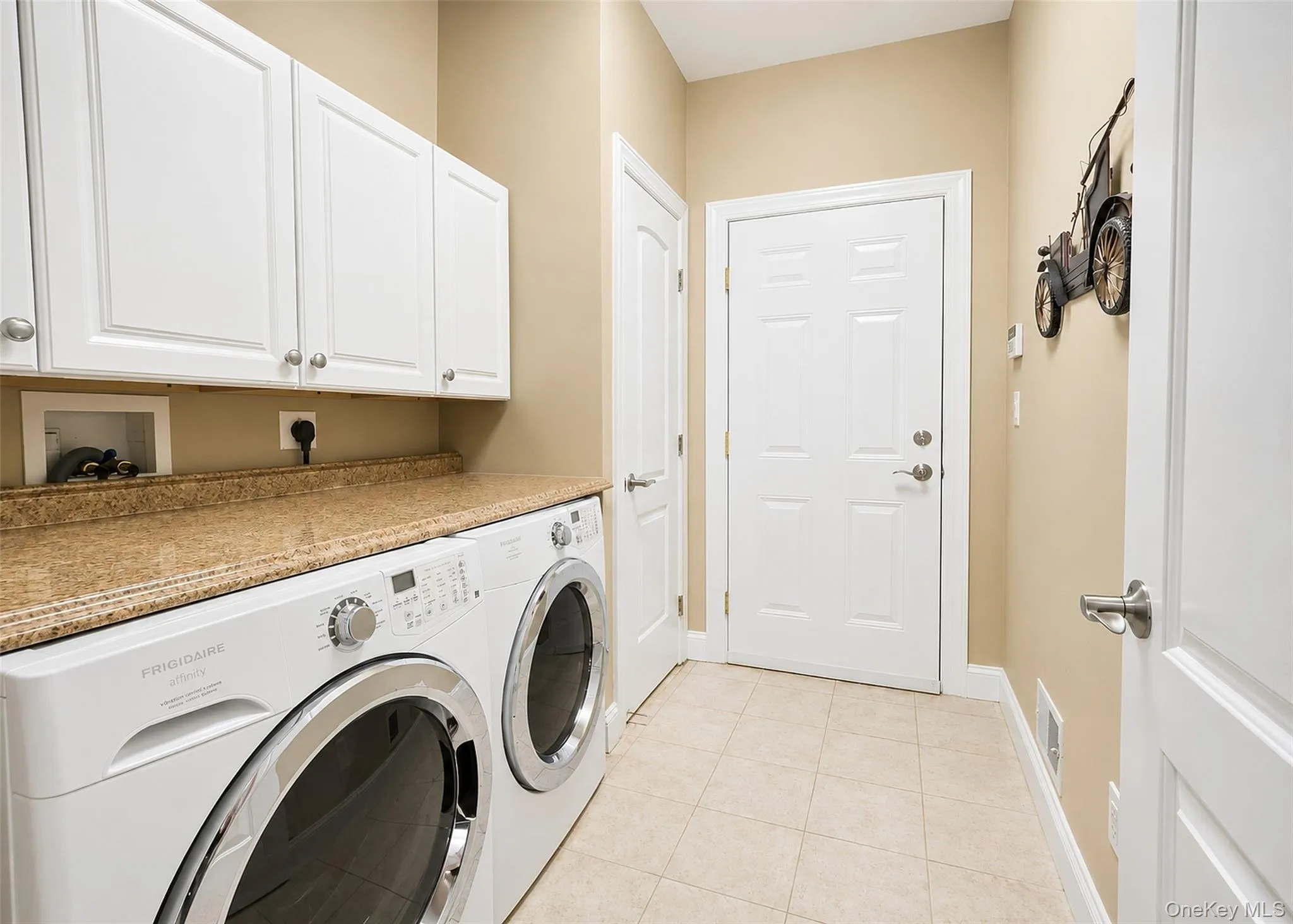 Laundry Rm W/Front Loading Frigidaire Washer/Dryer, Cabinets, Storage Closet, & Tile Flooring. Laundry Rm W/Front Loading Frigidaire Washer/Dryer, Cabinets, Storage Closet, & Tile Flooring.