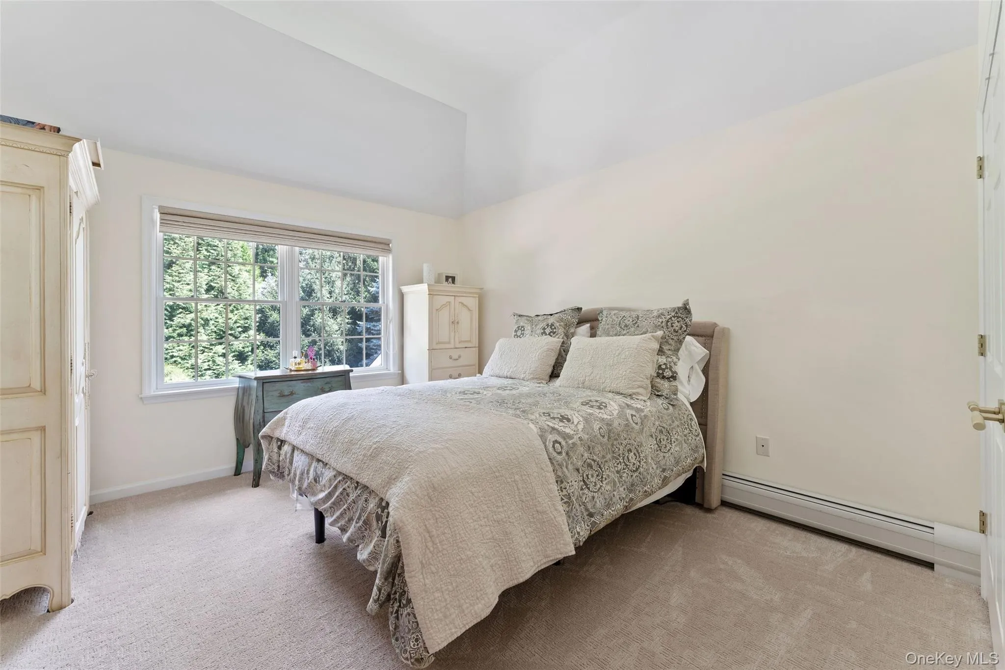Bedroom with light carpet, lofted ceiling, and a baseboard radiator Bedroom with light carpet, lofted ceiling, and a baseboard radiator