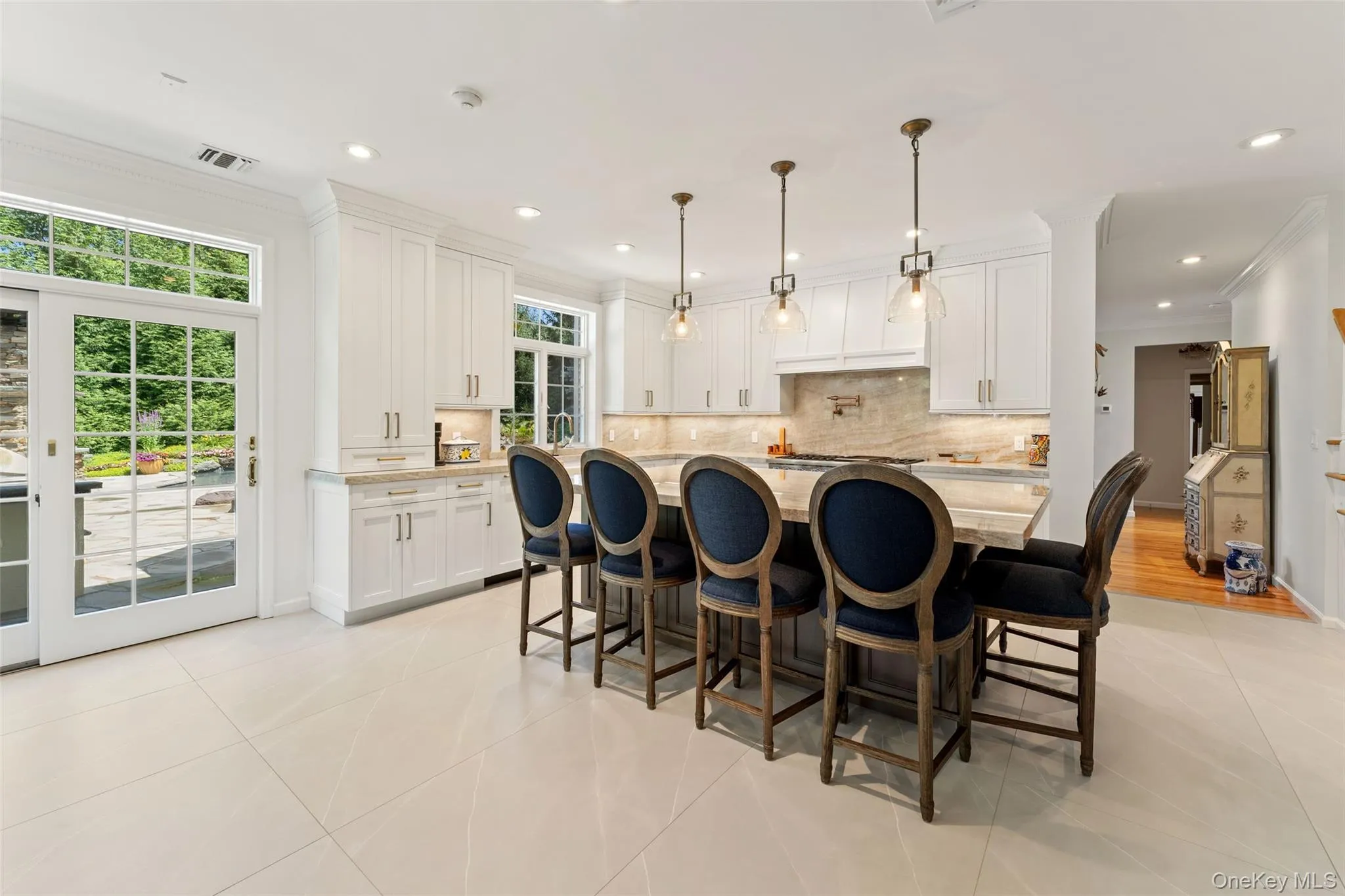 Kitchen with ornamental molding, light tile patterned flooring, white cabinetry, decorative backsplash, and a center island Kitchen with ornamental molding, light tile patterned flooring, white cabinetry, decorative backsplash, and a center island