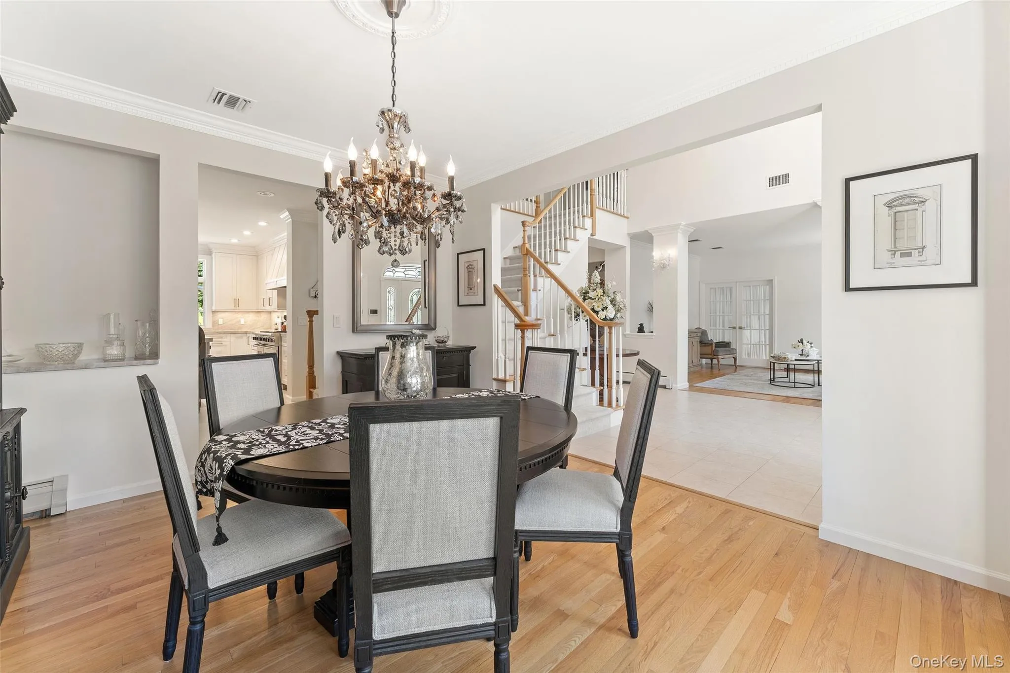 Dining room with stairway, crown molding, a chandelier, and light wood finished floors Dining room with stairway, crown molding, a chandelier, and light wood finished floors
