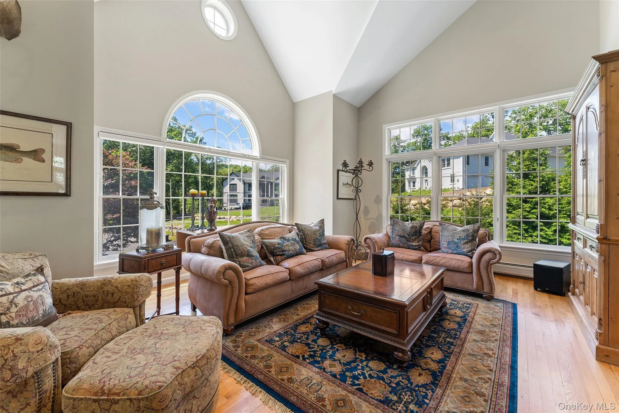 Living room with high vaulted ceiling, light wood-type flooring, and a baseboard heating unit Living room with high vaulted ceiling, light wood-type flooring, and a baseboard heating unit