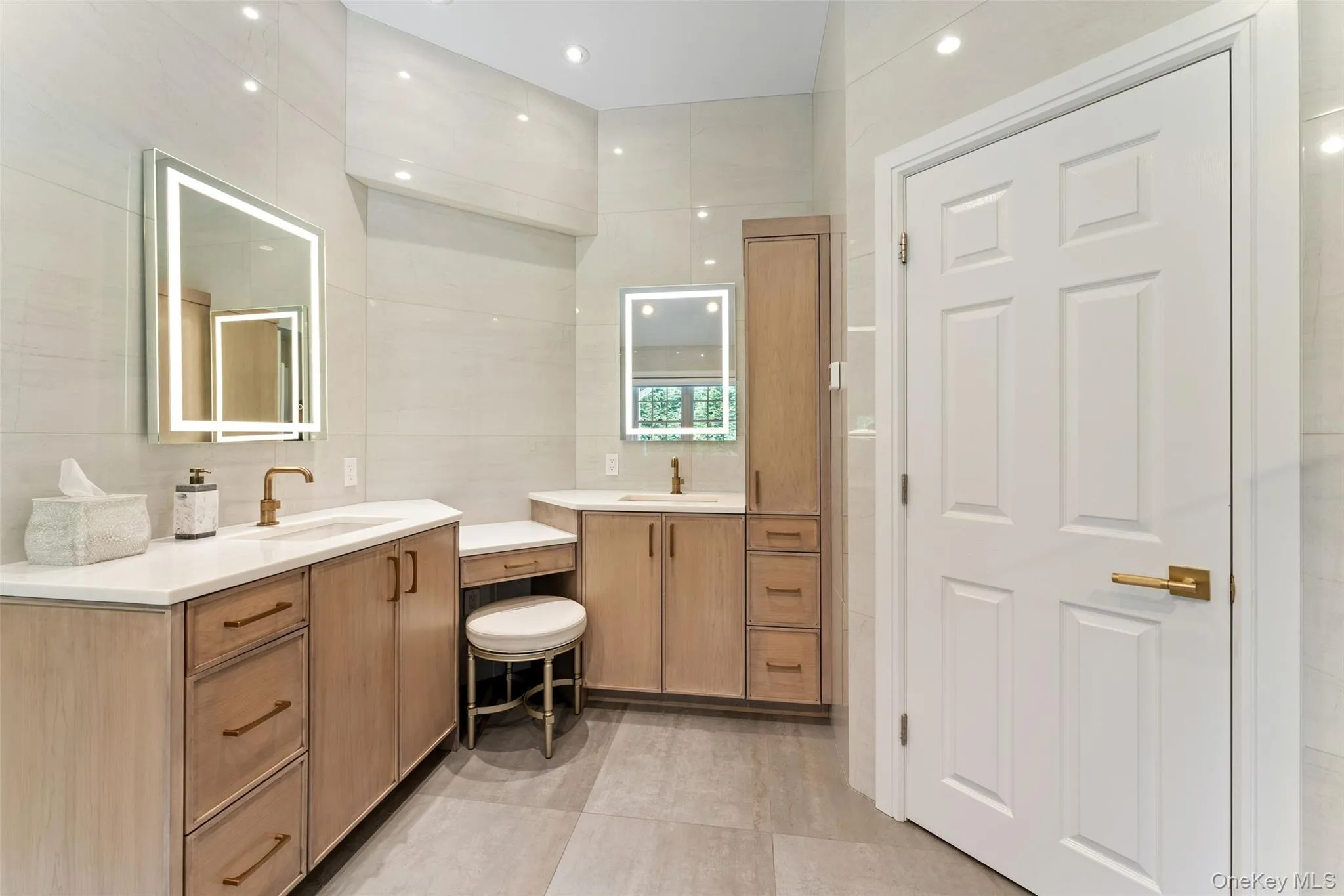 Bathroom with two vanities, tile walls, recessed lighting, and tile patterned flooring Bathroom with two vanities, tile walls, recessed lighting, and tile patterned flooring