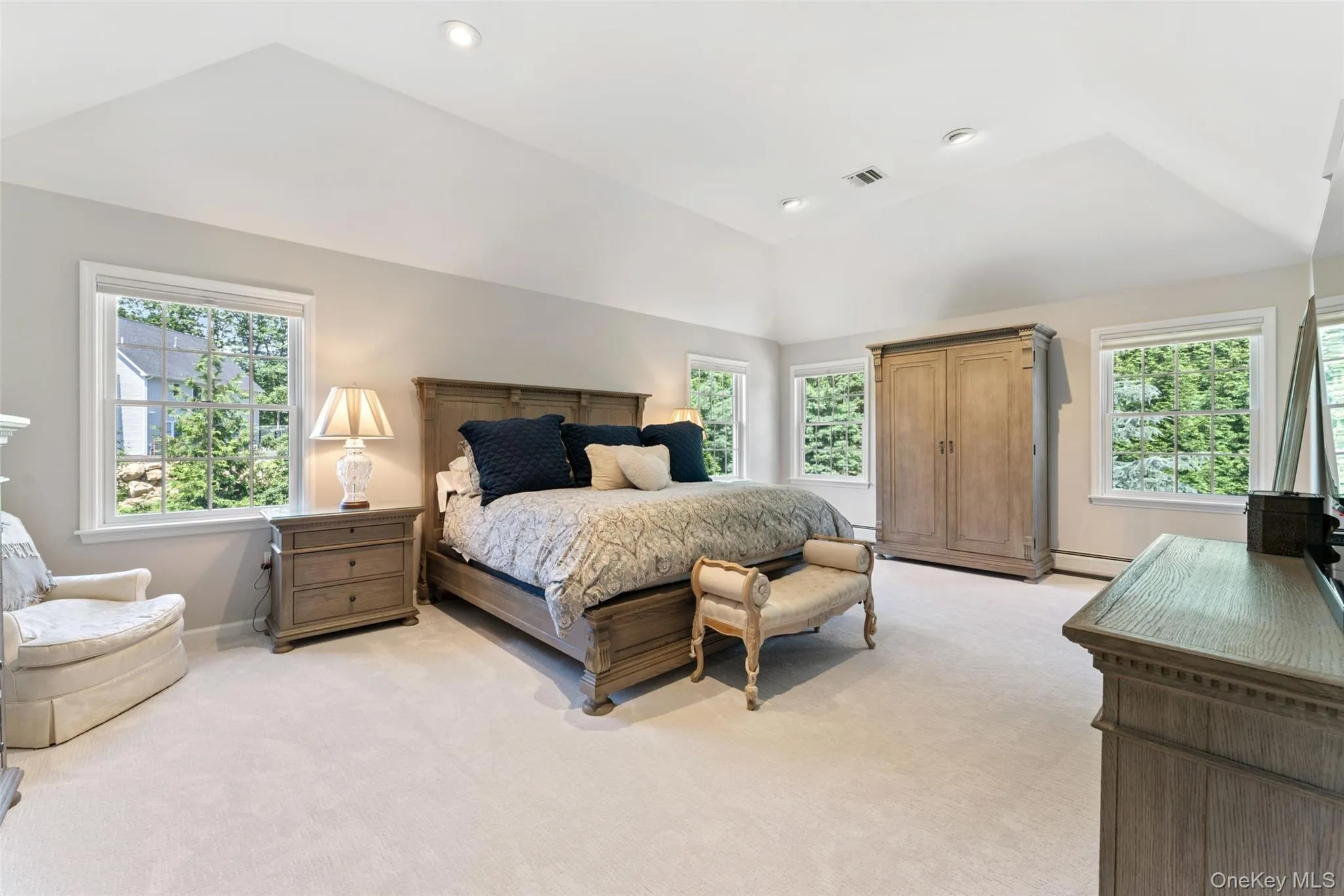 Bedroom featuring multiple windows, vaulted ceiling, light carpet, recessed lighting, and a baseboard radiator Bedroom featuring multiple windows, vaulted ceiling, light carpet, recessed lighting, and a baseboard radiator