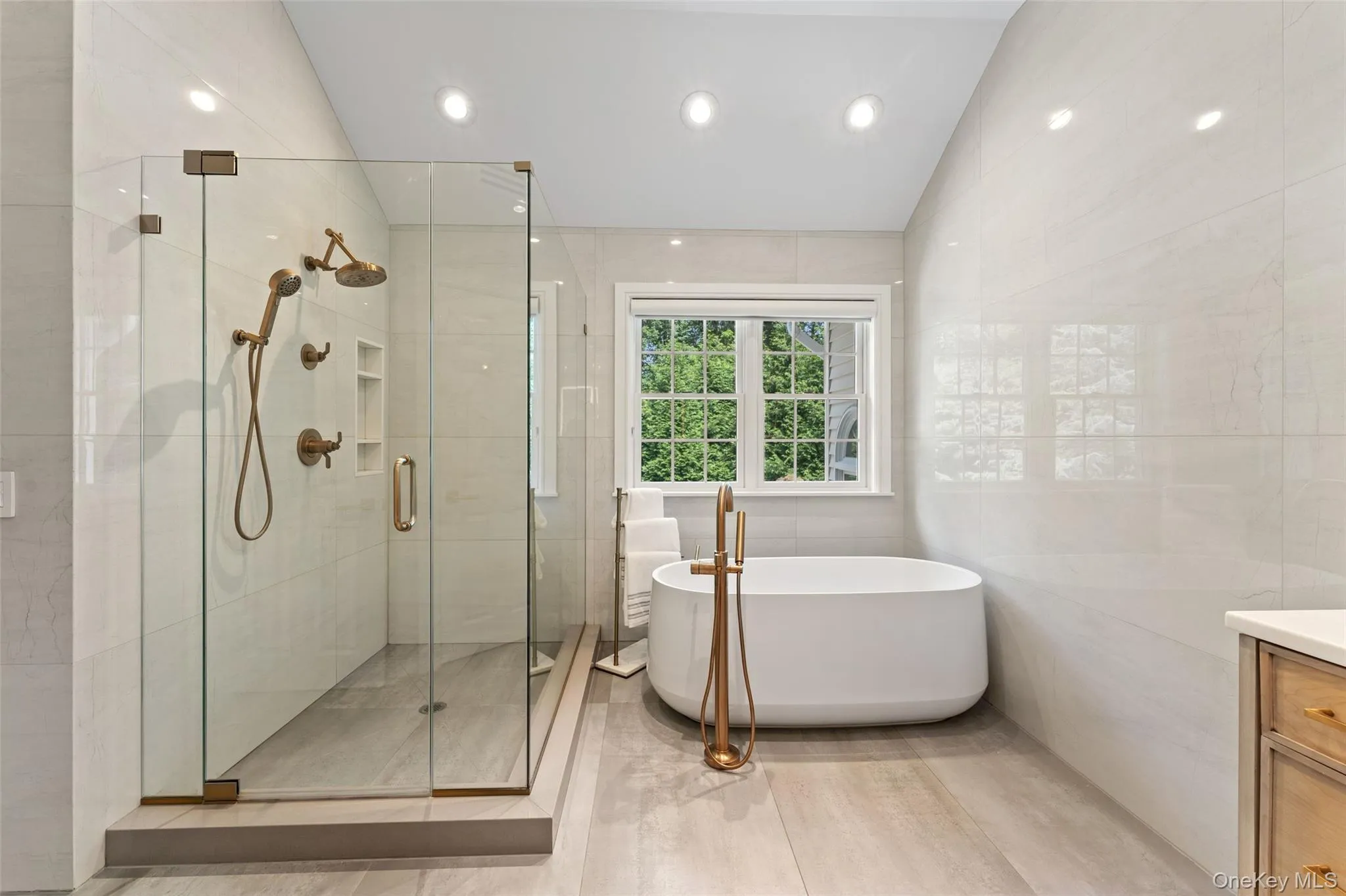Full bathroom featuring tile walls, lofted ceiling, a soaking tub, vanity, and a stall shower Full bathroom featuring tile walls, lofted ceiling, a soaking tub, vanity, and a stall shower
