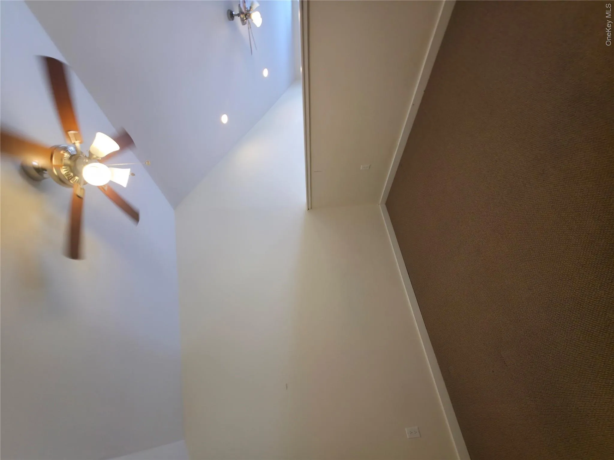 Empty room with lofted ceiling, ceiling fan, dark carpet, and baseboards Empty room with lofted ceiling, ceiling fan, dark carpet, and baseboards