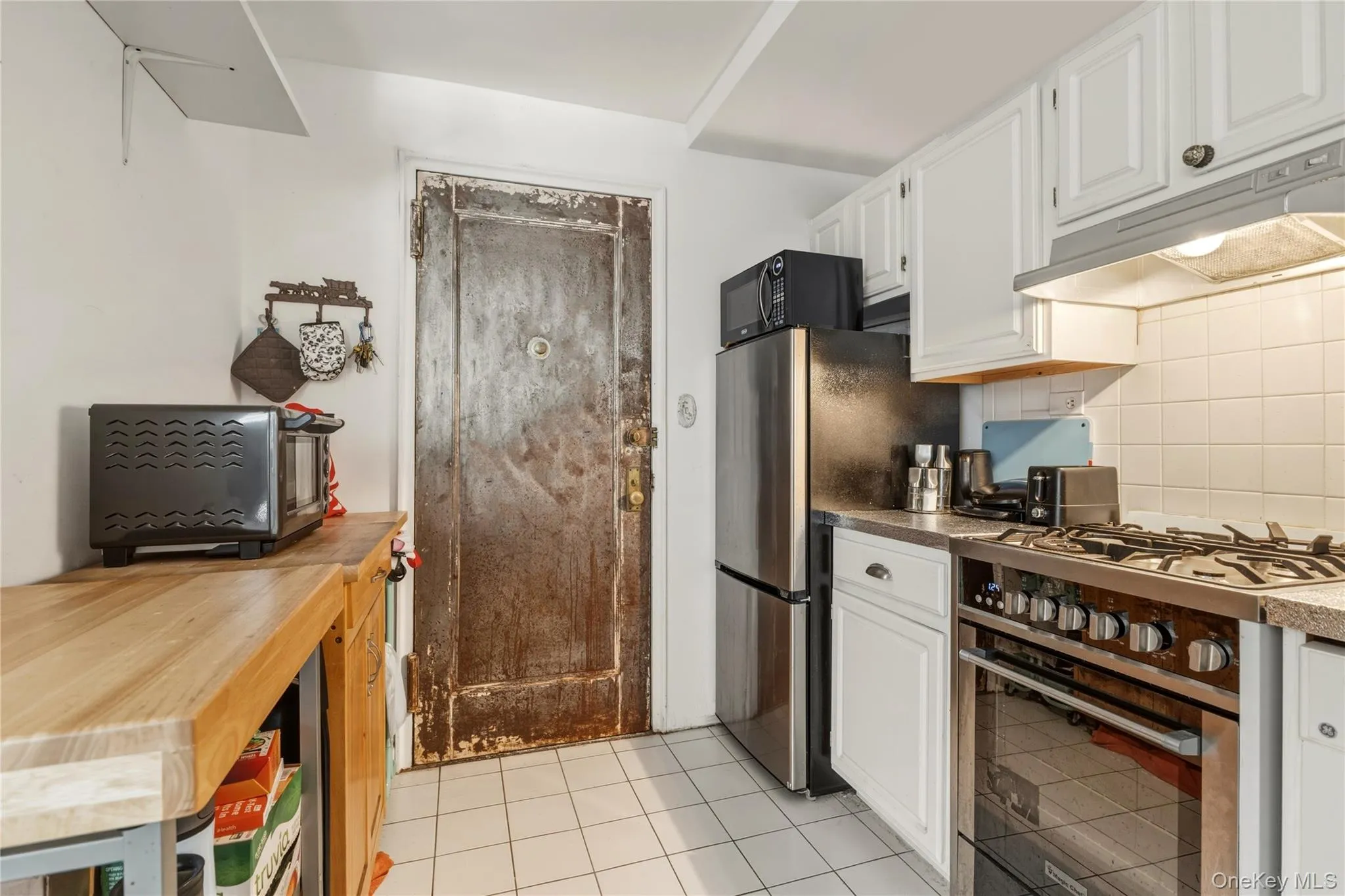 Kitchen featuring white cabinetry, a built-in stainless steel range, and a tiled backsplash Kitchen featuring white cabinetry, a built-in stainless steel range, and a tiled backsplash