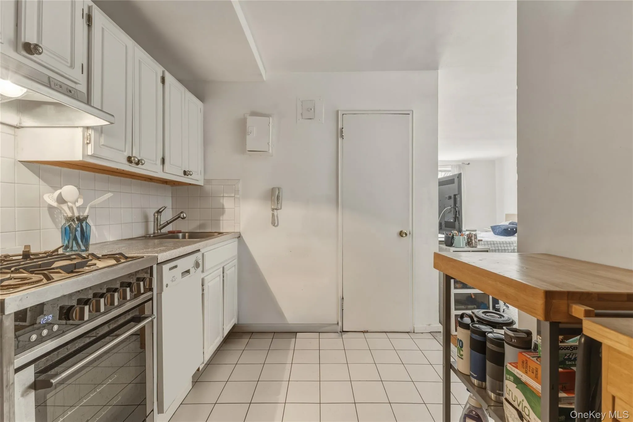 Kitchen featuring white cabinetry, a stainless steel range, a built-in dishwasher, and white tile flooring Kitchen featuring white cabinetry, a stainless steel range, a built-in dishwasher, and white tile flooring
