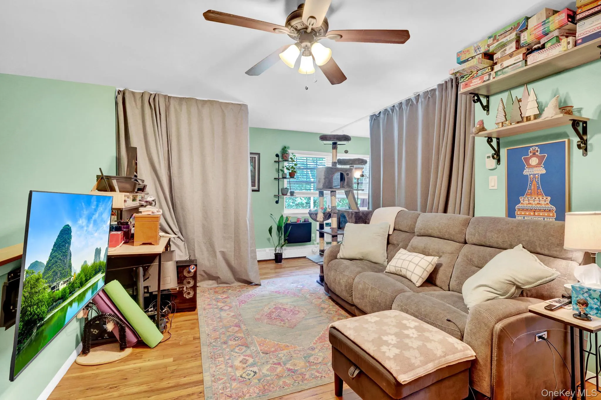 Living area featuring wood-finish flooring, a ceiling fan with integrated lighting, and light green wall accents Living area featuring wood-finish flooring, a ceiling fan with integrated lighting, and light green wall accents