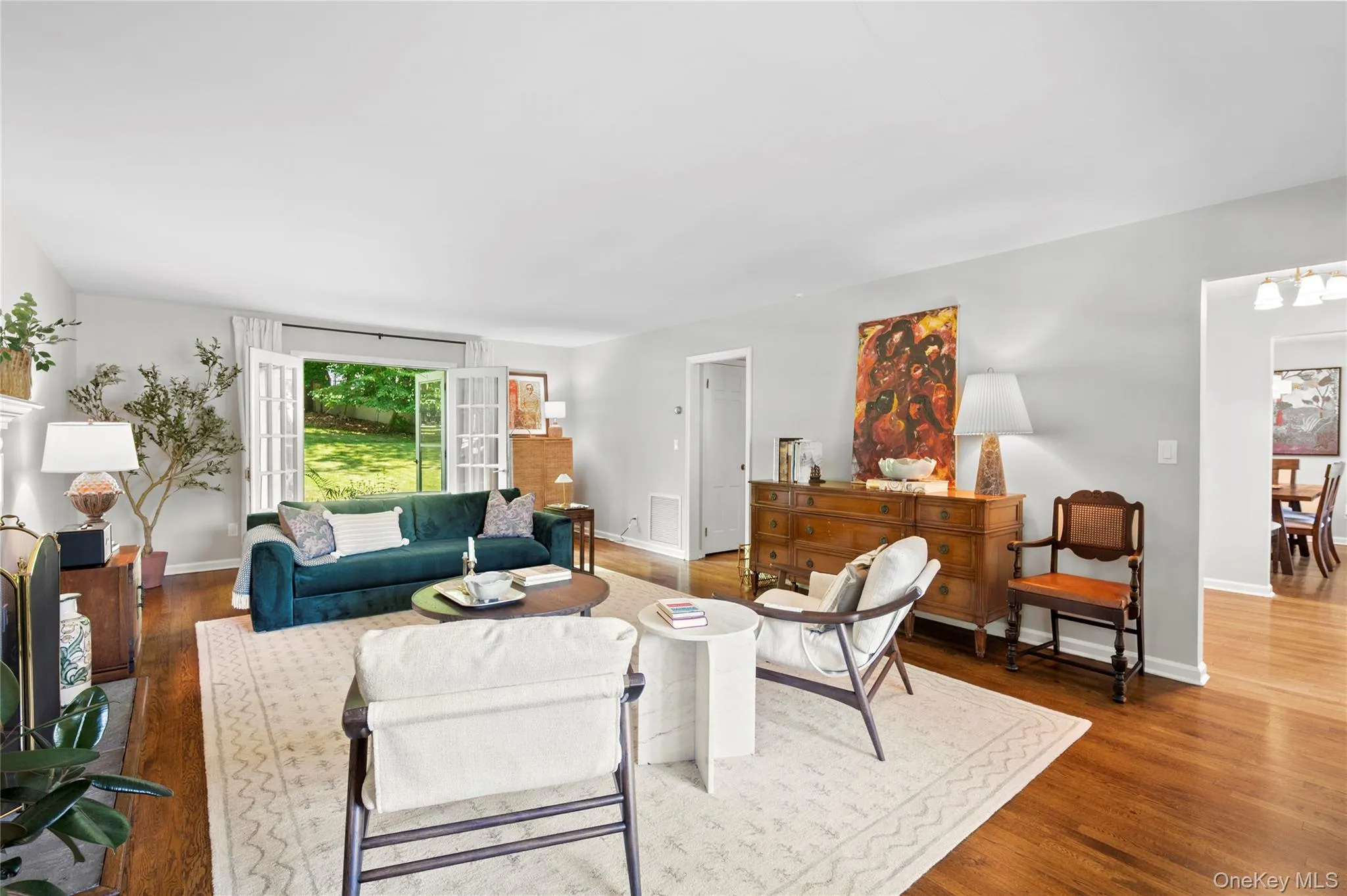Elegant living room showcasing hardwood floors and a charming fireplace, with French doors creating an effortless indoor-outdoor flow to the patio. Elegant living room showcasing hardwood floors and a charming fireplace, with French doors creating an effortless indoor-outdoor flow to the patio.