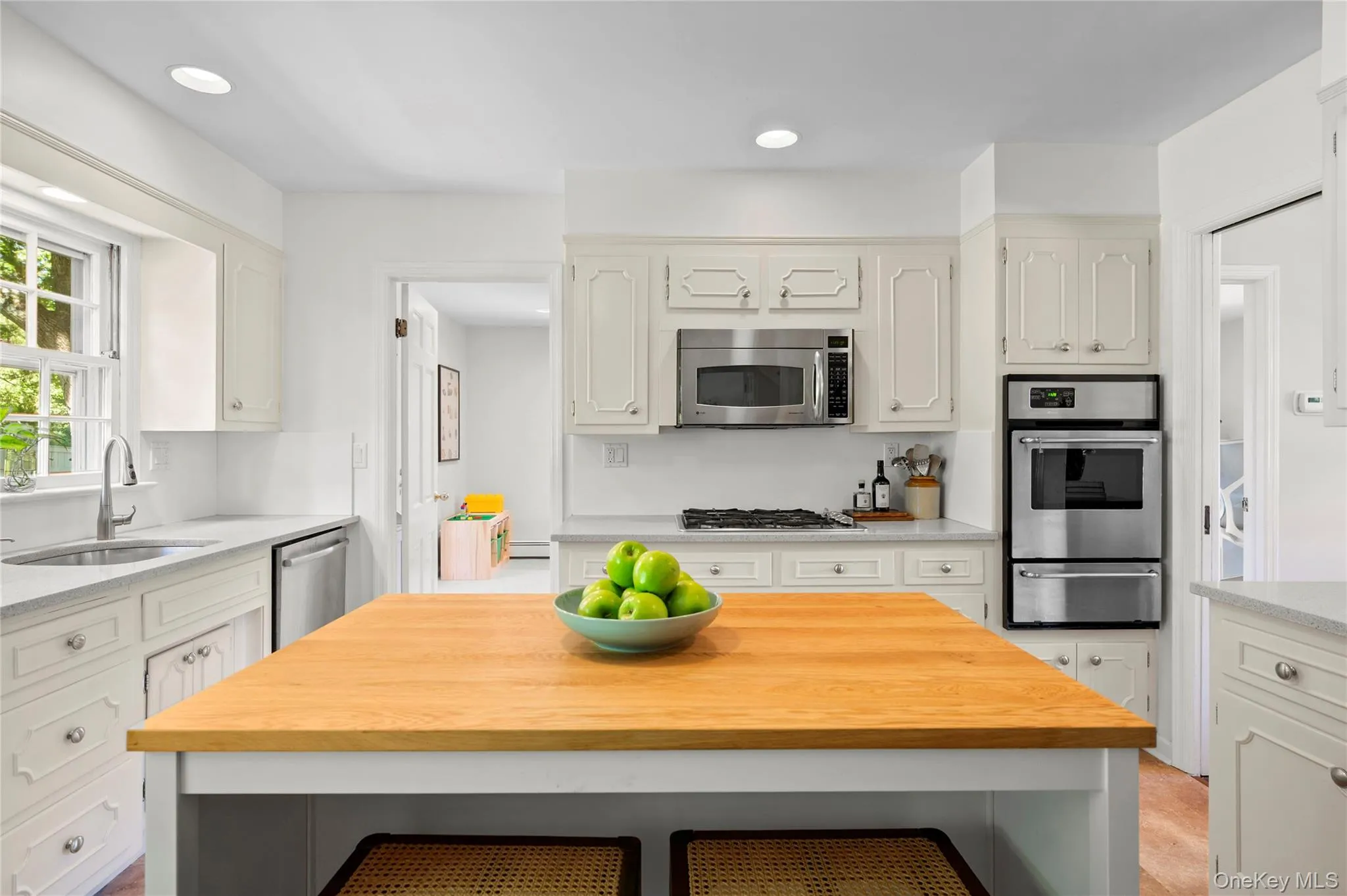 Kitchen featuring white cabinetry, integrated stainless steel appliances, granite countertops. Kitchen featuring white cabinetry, integrated stainless steel appliances, granite countertops.