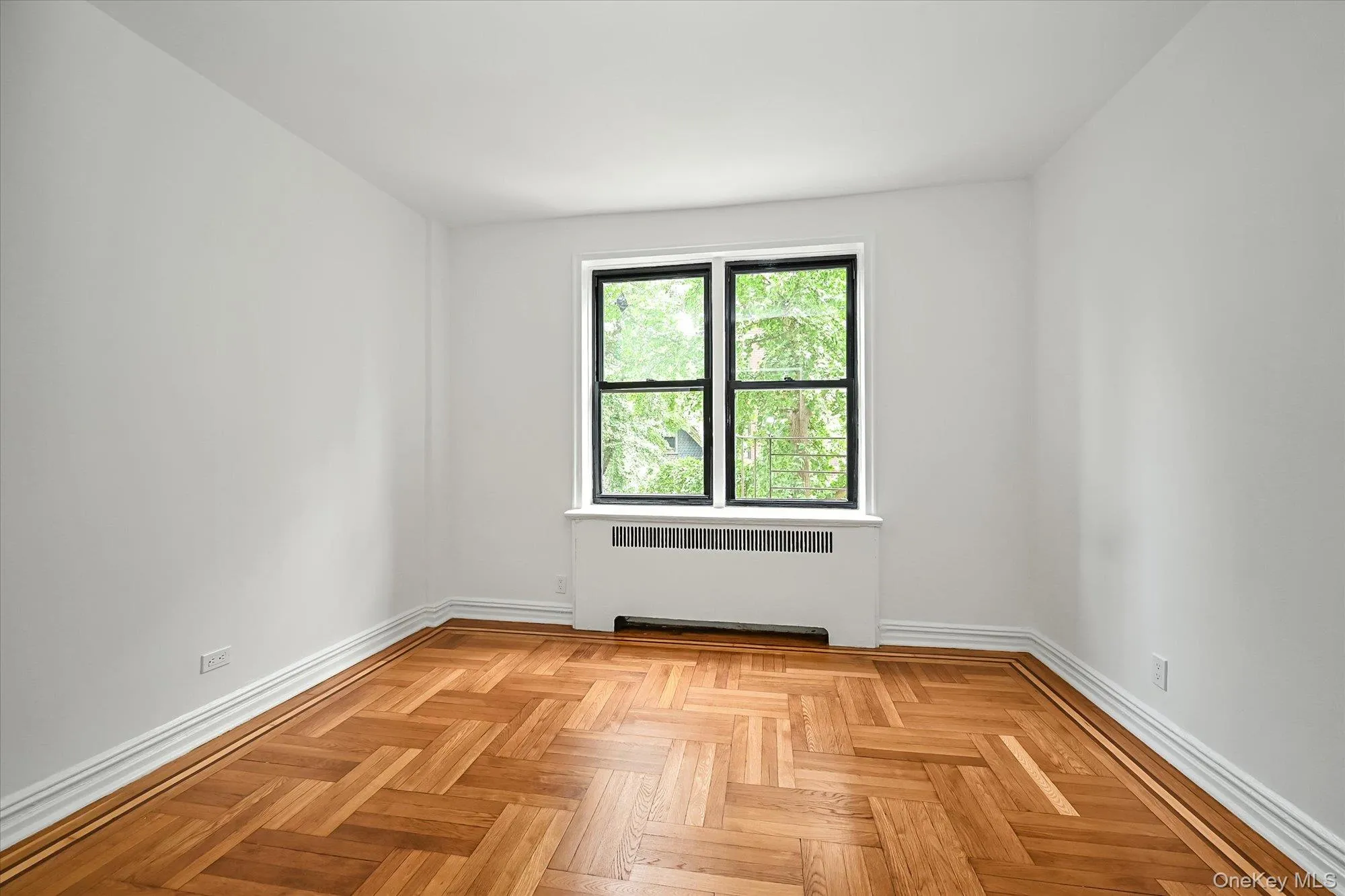 Herringbone wood-finish flooring with perimeter border, white baseboards, and neutral wall tones. Herringbone wood-finish flooring with perimeter border, white baseboards, and neutral wall tones.