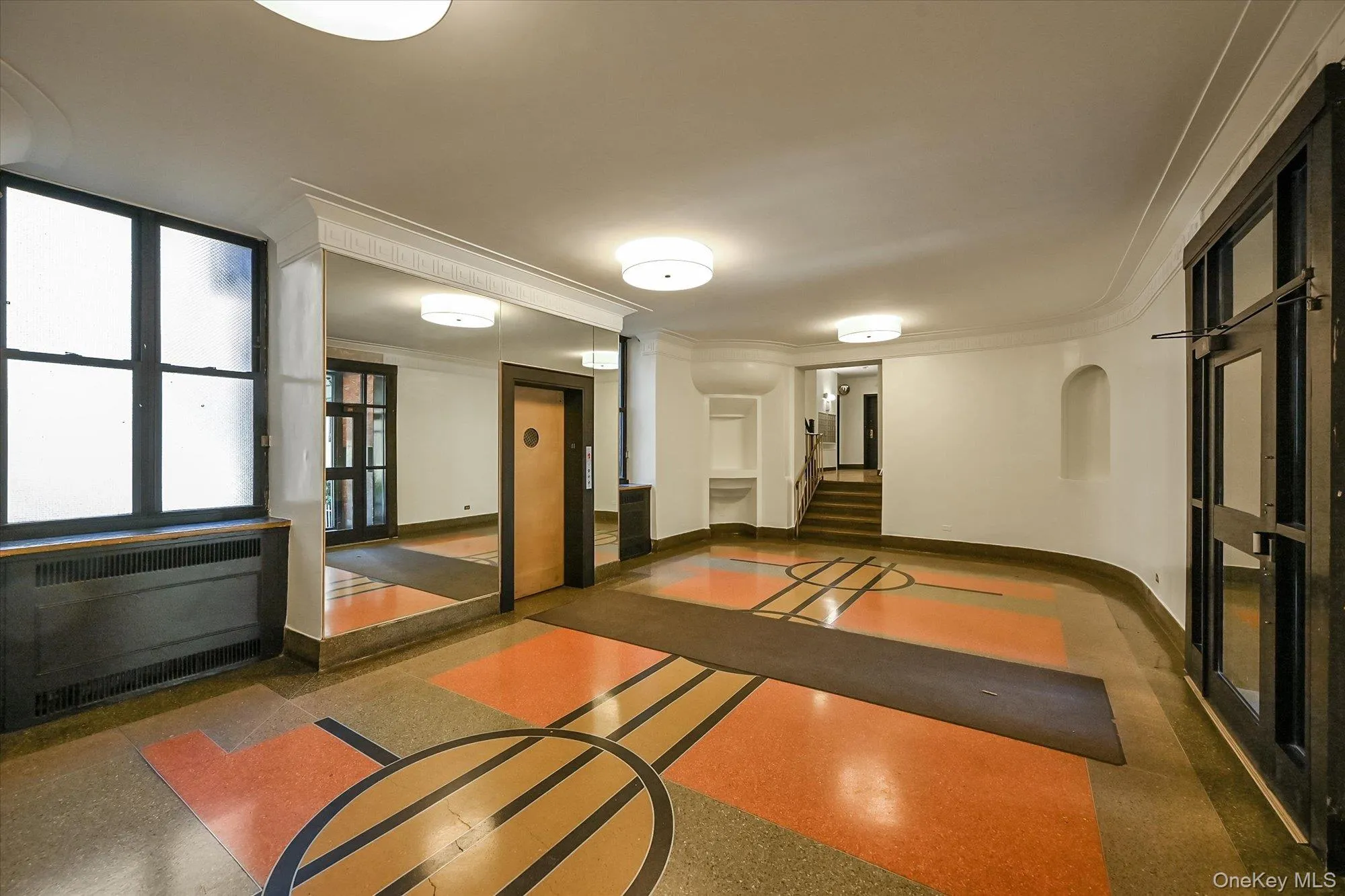 Entry featuring a patterned terrazzo floor, large framed mirror, and curved wall details. Entry featuring a patterned terrazzo floor, large framed mirror, and curved wall details.