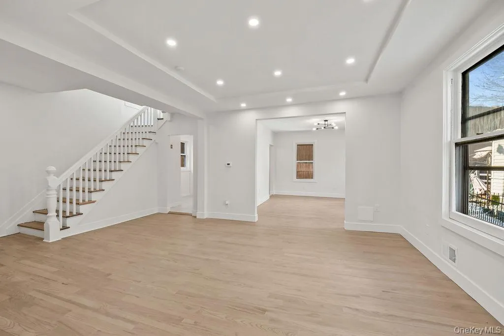 Unfurnished living room featuring recessed lighting, stairs, light wood-style flooring, and a tray ceiling Unfurnished living room featuring recessed lighting, stairs, light wood-style flooring, and a tray ceiling