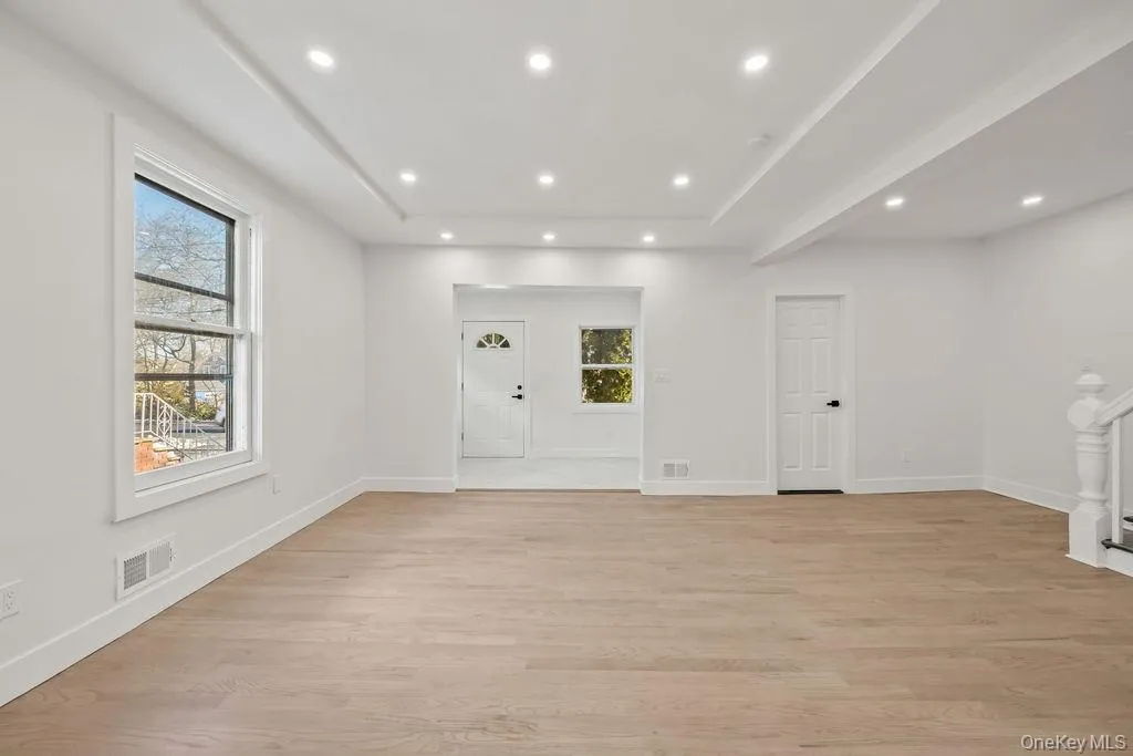 Entrance foyer with light wood-style floors, recessed lighting, and a tray ceiling Entrance foyer with light wood-style floors, recessed lighting, and a tray ceiling