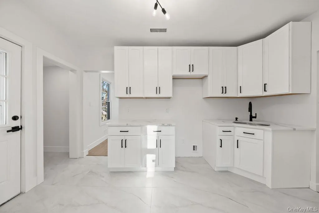 Laundry area featuring light marble finish flooring and a sink Laundry area featuring light marble finish flooring and a sink