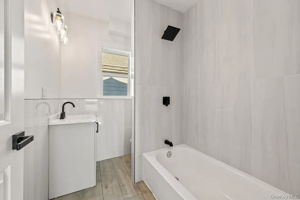 Bathroom featuring vanity, bathtub / shower combination, and wood tiled floors Bathroom featuring vanity, bathtub / shower combination, and wood tiled floors