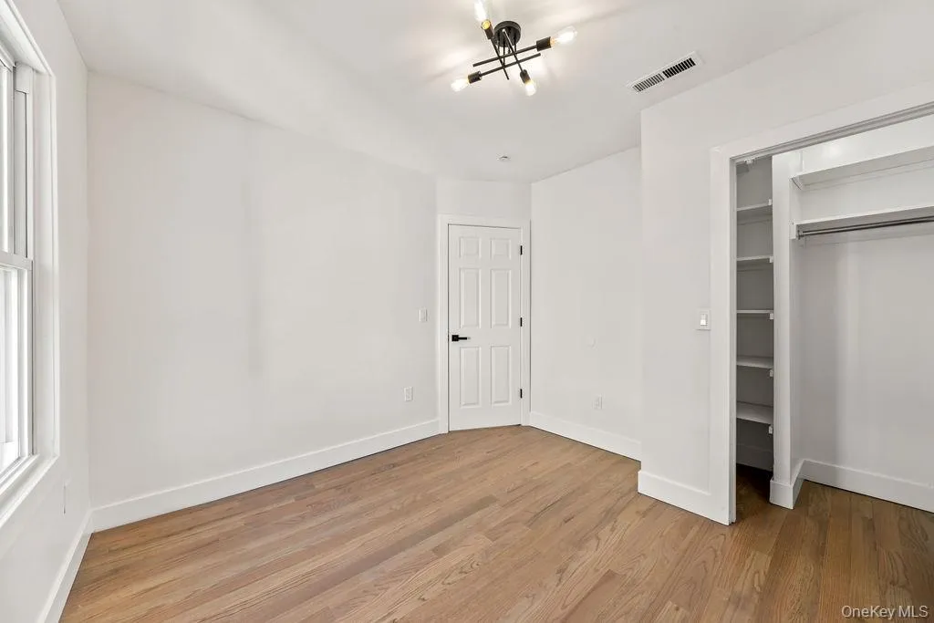 Unfurnished bedroom featuring light wood-type flooring and a walk in closet Unfurnished bedroom featuring light wood-type flooring and a walk in closet