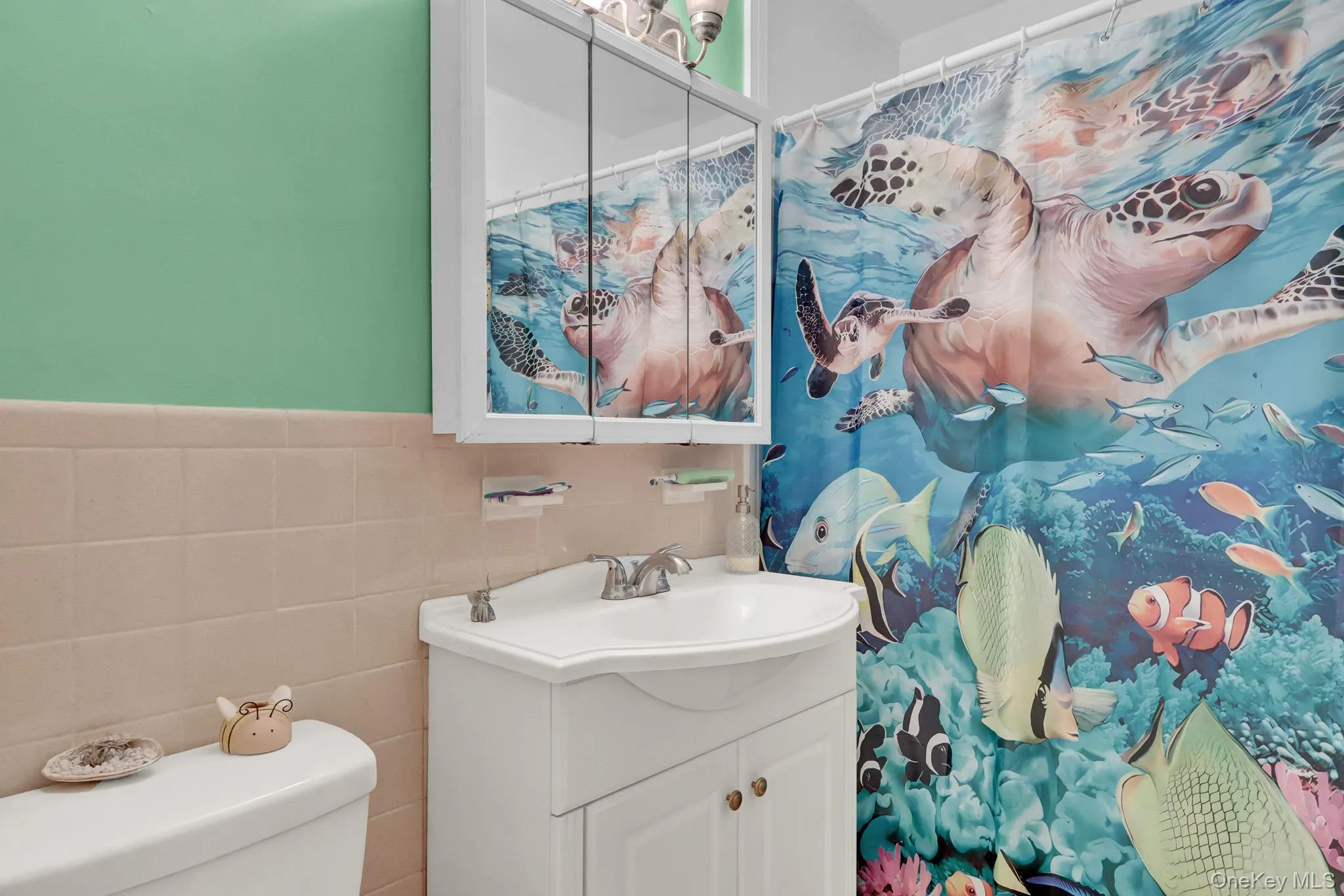 Bathroom featuring a white toilet, white vanity with integrated sink, and a mirrored medicine cabinet Bathroom featuring a white toilet, white vanity with integrated sink, and a mirrored medicine cabinet