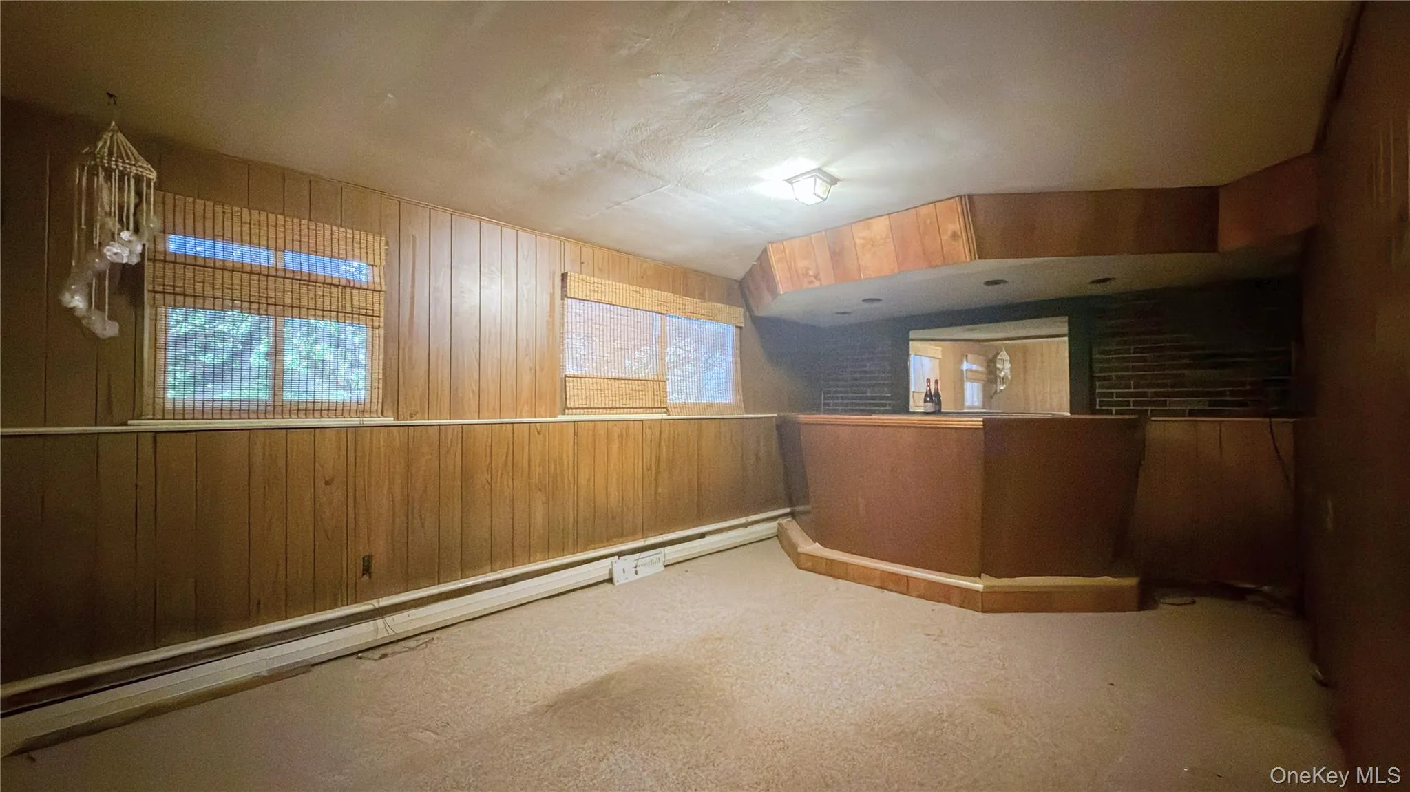 Lower level den with wood bar, wood walls, carpet and windows Lower level den with wood bar, wood walls, carpet and windows