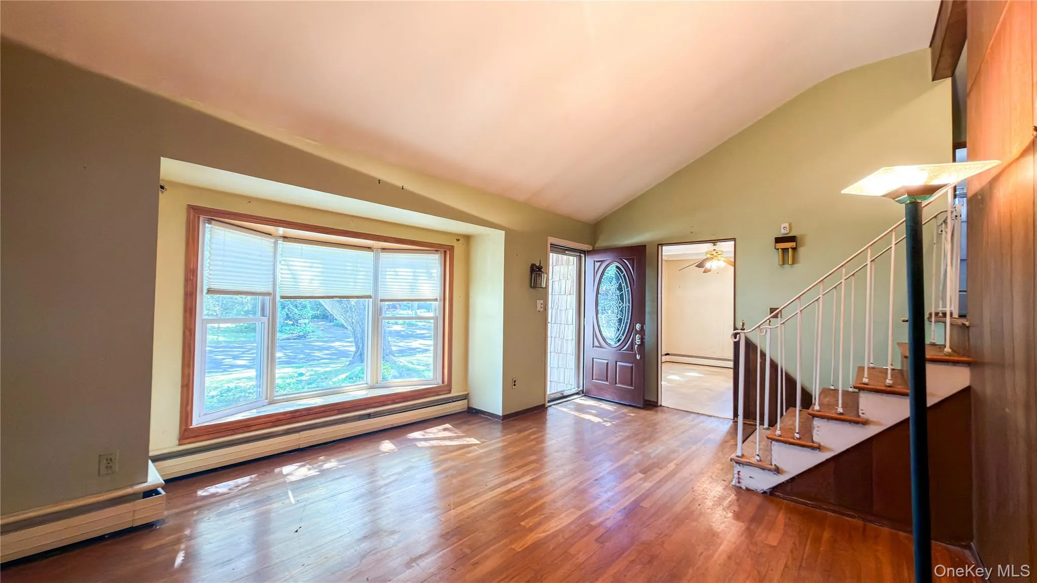 Living room with bay window, wood floors, wood walls and stairs with metal handrails leading to second floor Living room with bay window, wood floors, wood walls and stairs with metal handrails leading to second floor