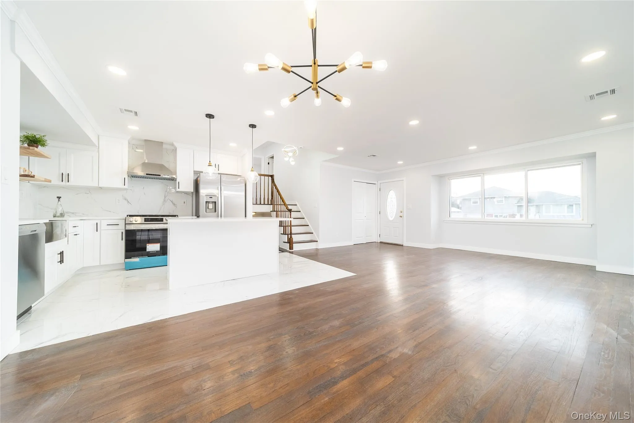 Unfurnished living room with ornamental molding, stairway, light wood-style floors, a chandelier, and recessed lighting Unfurnished living room with ornamental molding, stairway, light wood-style floors, a chandelier, and recessed lighting