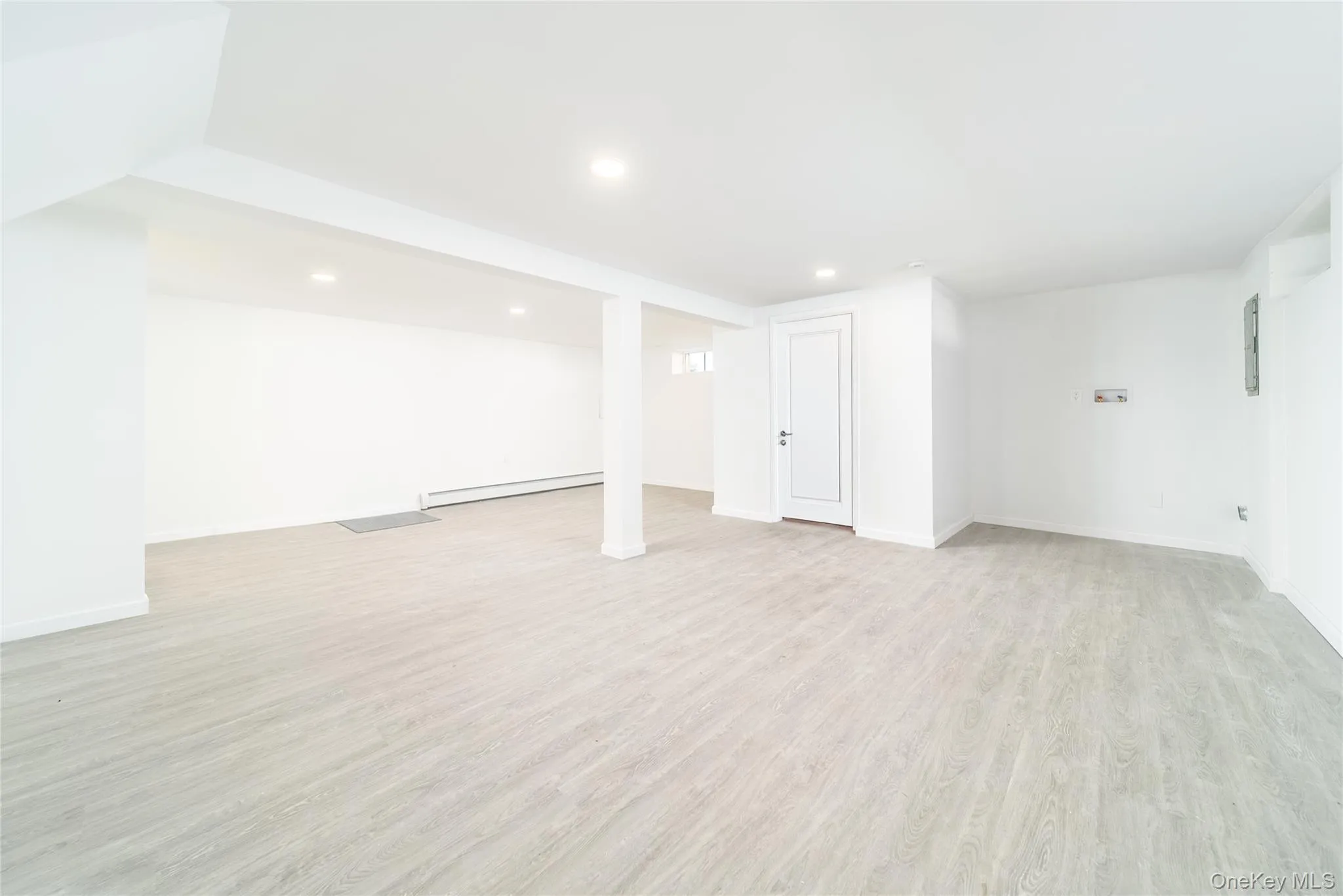 Finished below grade area featuring light wood finished floors, a baseboard heating unit, and recessed lighting Finished below grade area featuring light wood finished floors, a baseboard heating unit, and recessed lighting