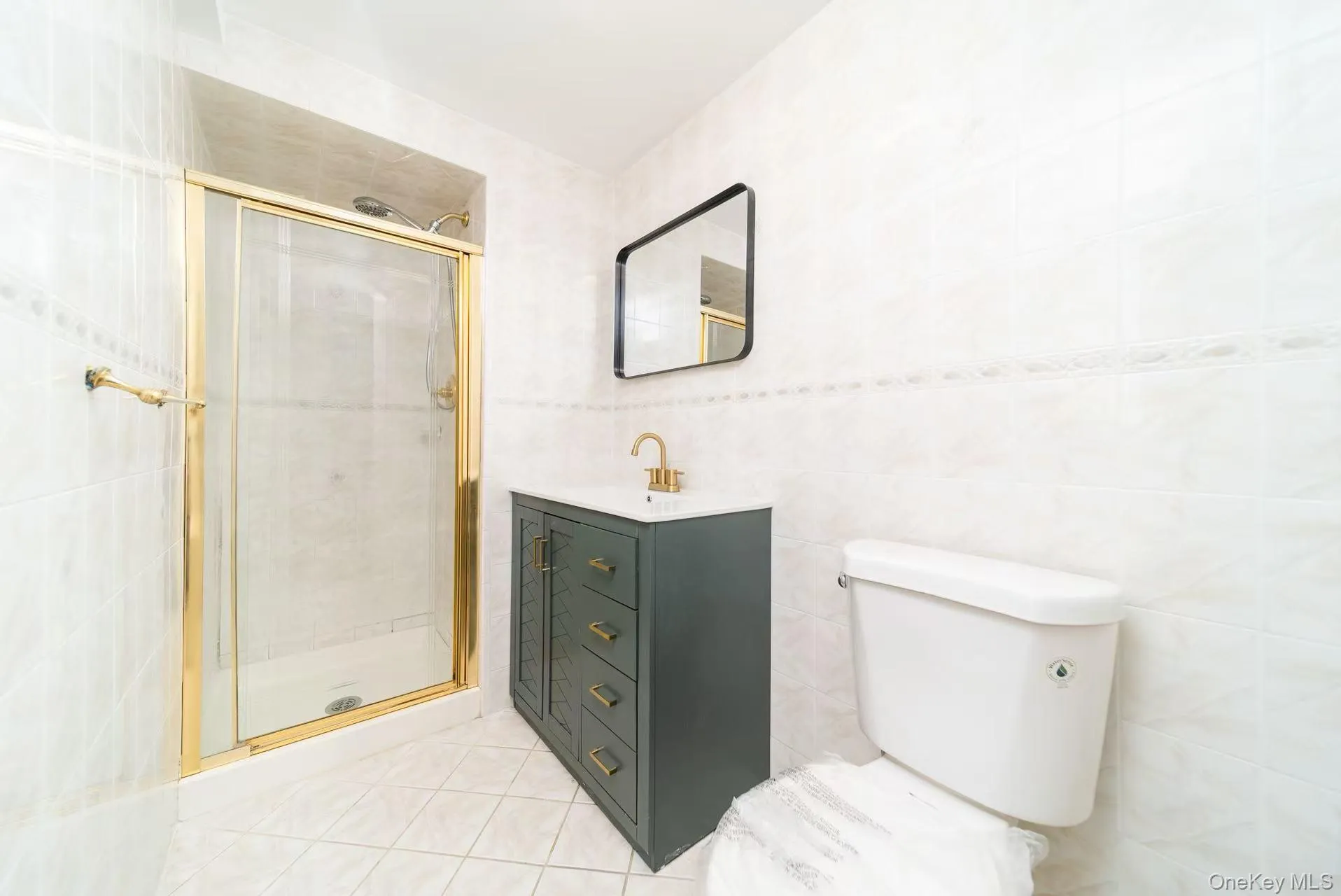 Bathroom featuring tile walls, a stall shower, vanity, and light tile patterned floors Bathroom featuring tile walls, a stall shower, vanity, and light tile patterned floors