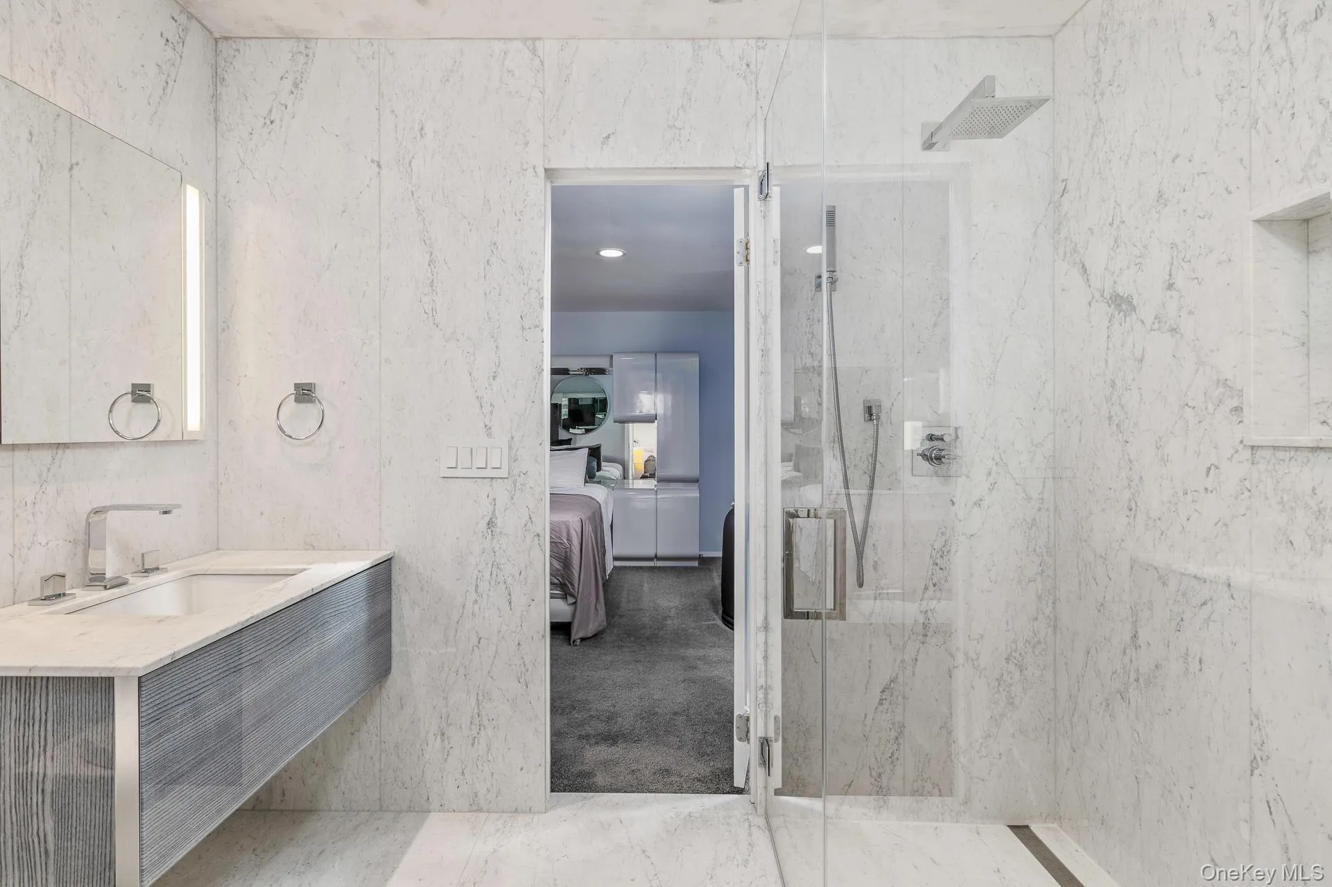 Bathroom with ensuite bath, vanity, a marble finish shower, light marble finish floors, and tile walls Bathroom with ensuite bath, vanity, a marble finish shower, light marble finish floors, and tile walls