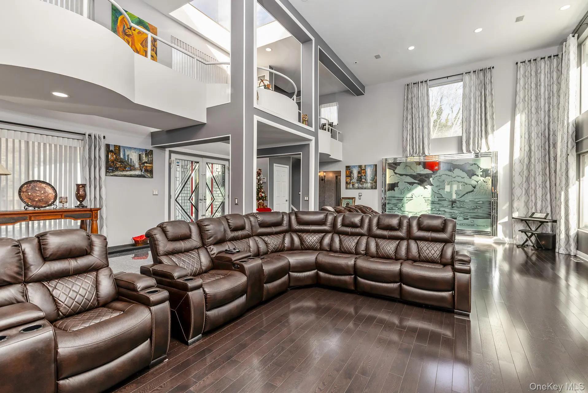 Living area with a towering ceiling, dark wood-style flooring, and recessed lighting Living area with a towering ceiling, dark wood-style flooring, and recessed lighting
